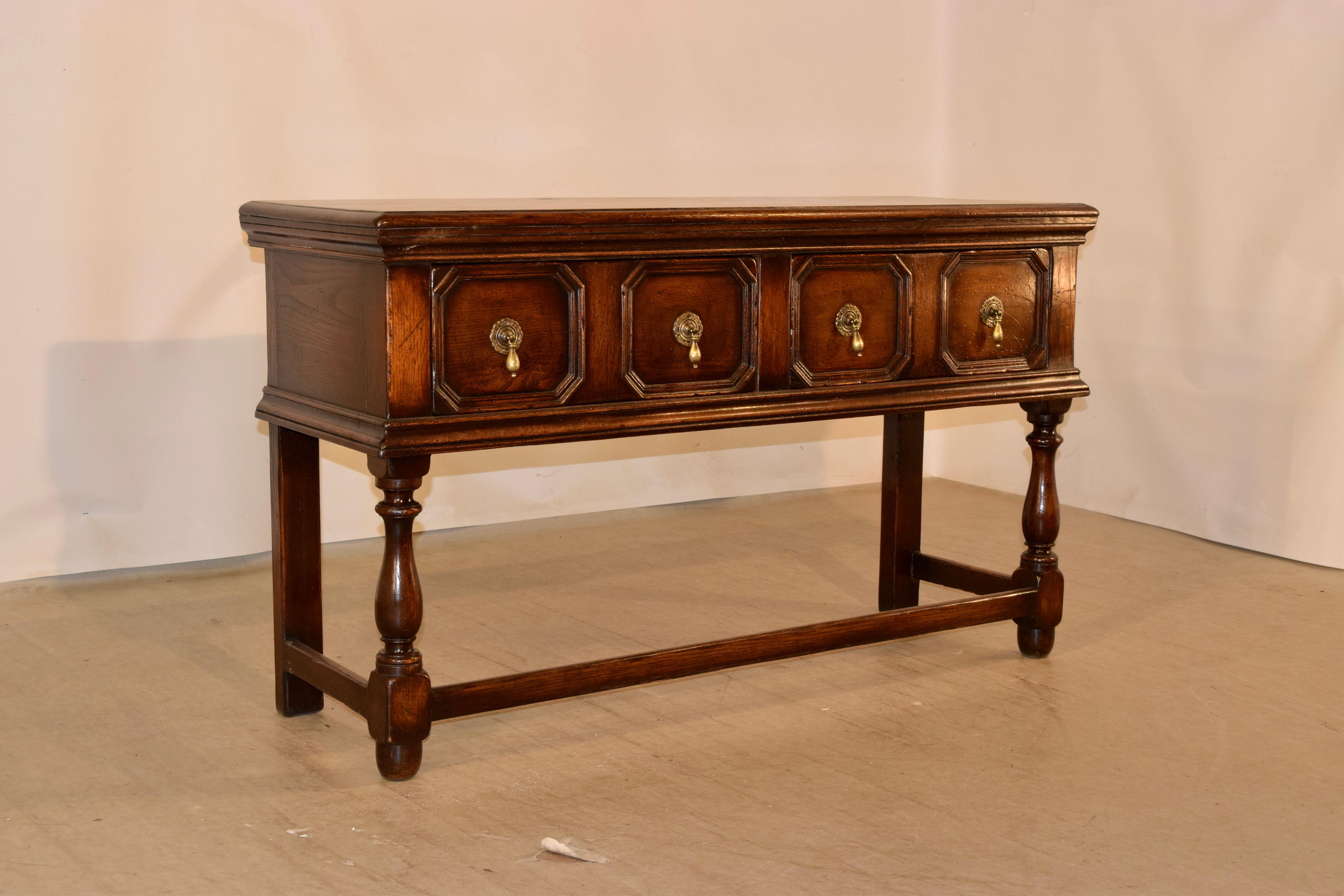 Late 19th century oak sideboard from England. The top has a beveled and molded edge, following down to simple sides and two raised paneled drawers in the front, with hand cast brass hardware. The legs are wonderfully hand-turned in the front and
