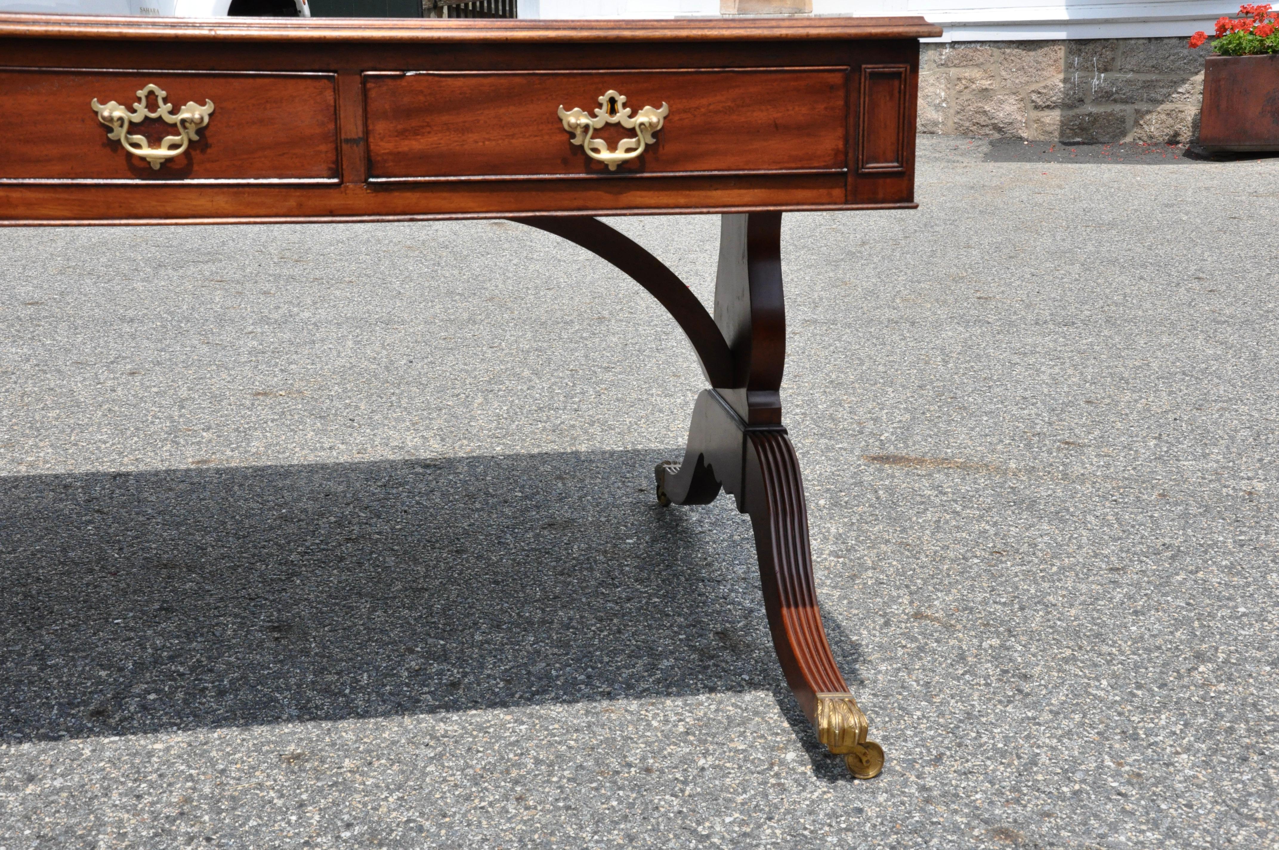 Late 19th century English Regency style leather top partners desk. Three drawers on both sides. Regency outswept legs and side supports. Original casters. Mahogany primary construction with oak secondary. Original leather top exhibiting beautifully