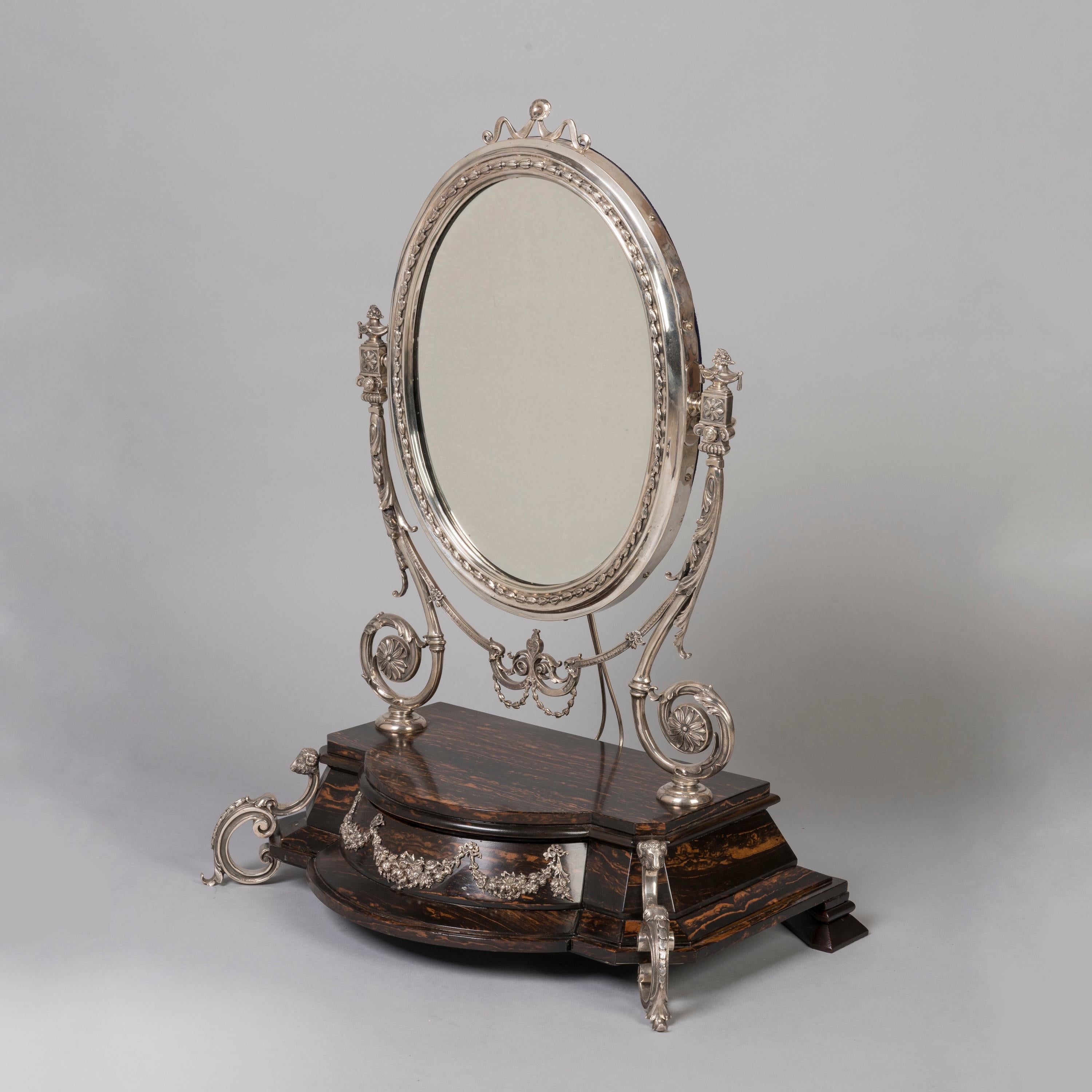 Un impressionante specchio da tavolo Coromandel con montatura d'argento
Da Mappin & Webb

Un oggetto molto insolito che combina il raro legno di coromandel e l'argento massiccio, lo specchio da toilette è sostenuto da una base di coromandel che