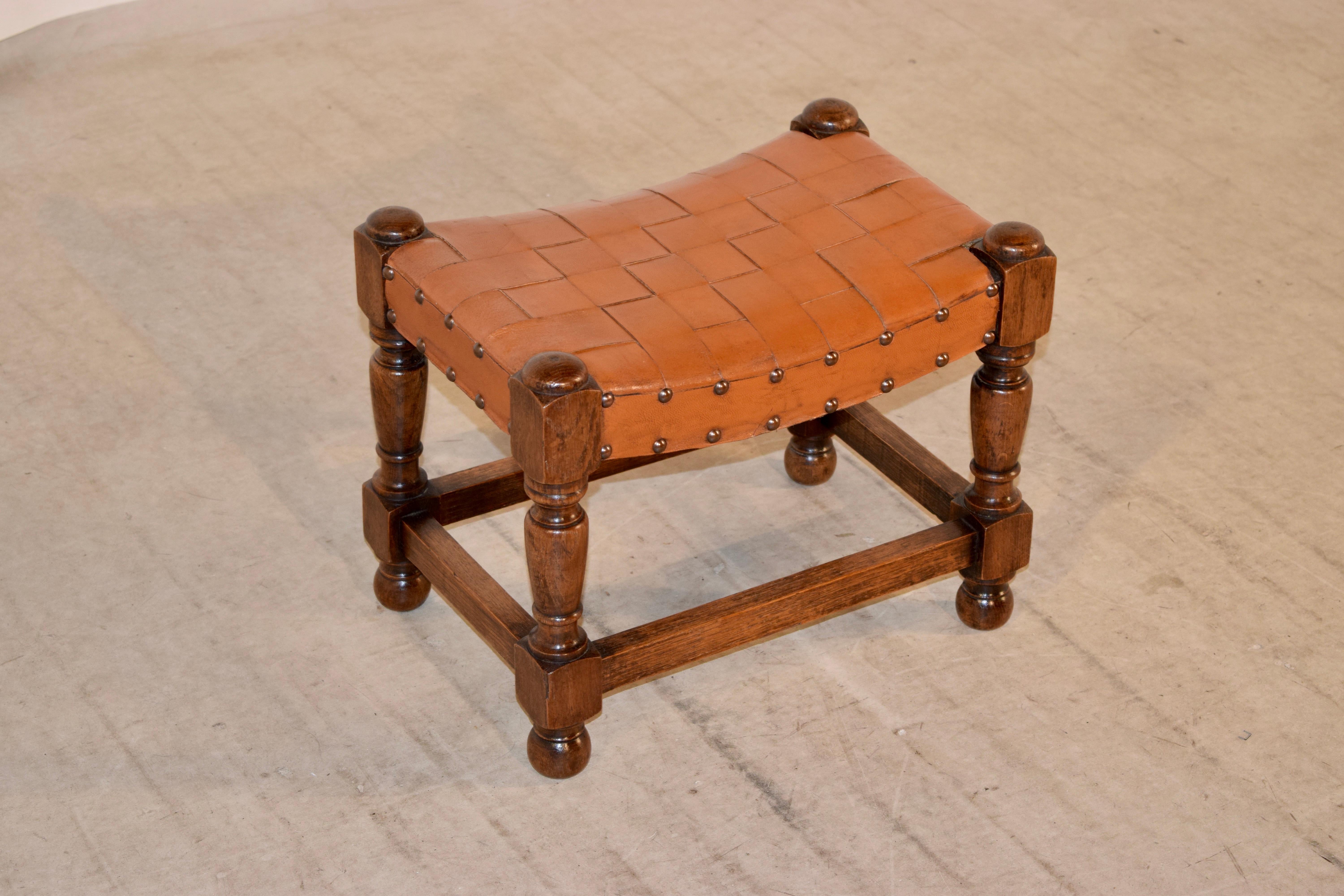 Late 19th century stool from England with a braided leather swayed top, following down to hand turned legs, joined by simple stretchers. Raised on turned feet.