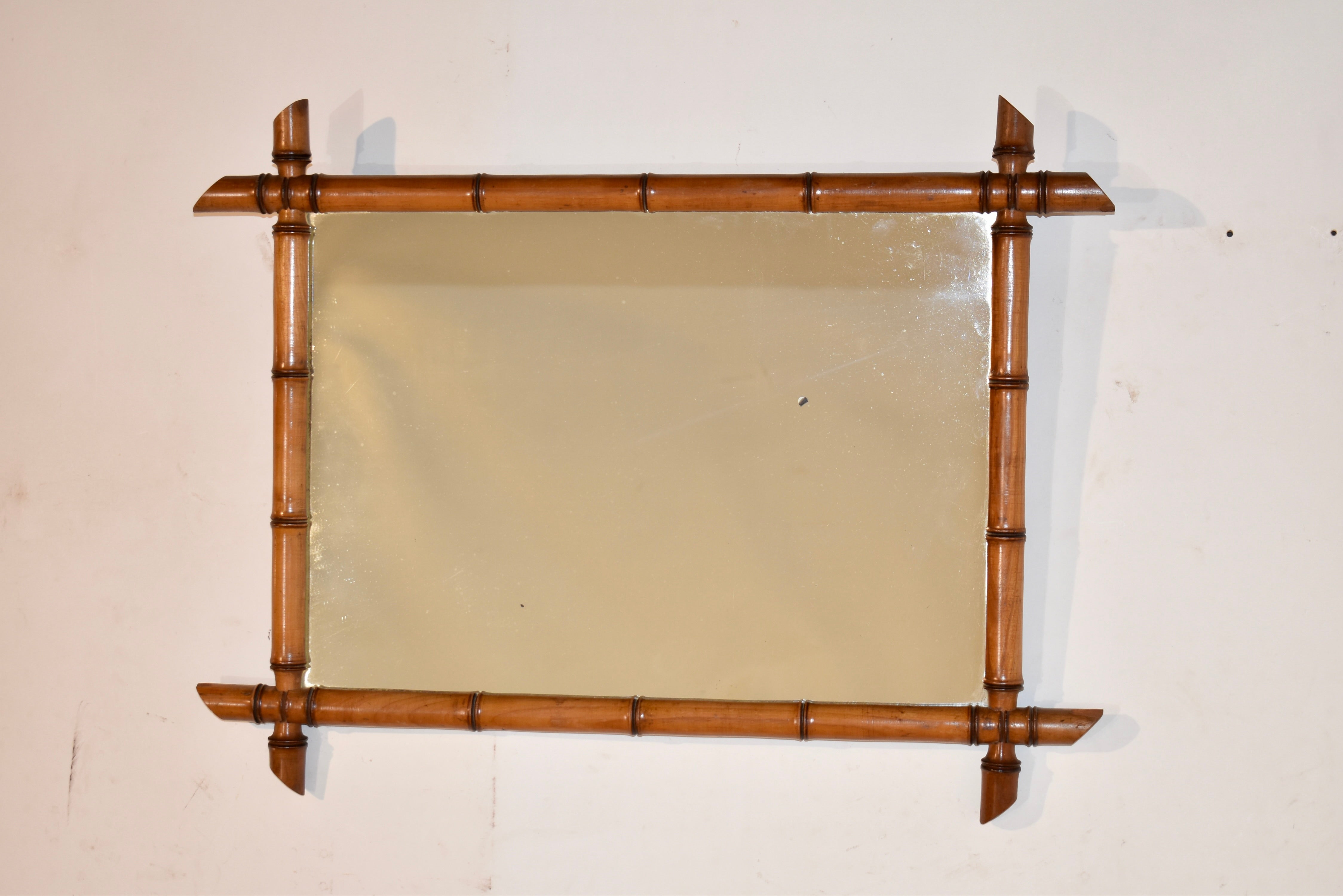Late 19th century faux bamboo framed mirror from France.  The frame is made from cherry and is hand turned to resemble bamboo.  It surrounds an old mirror, which has some losses to the mercury from age, for a timeless look of elegance and