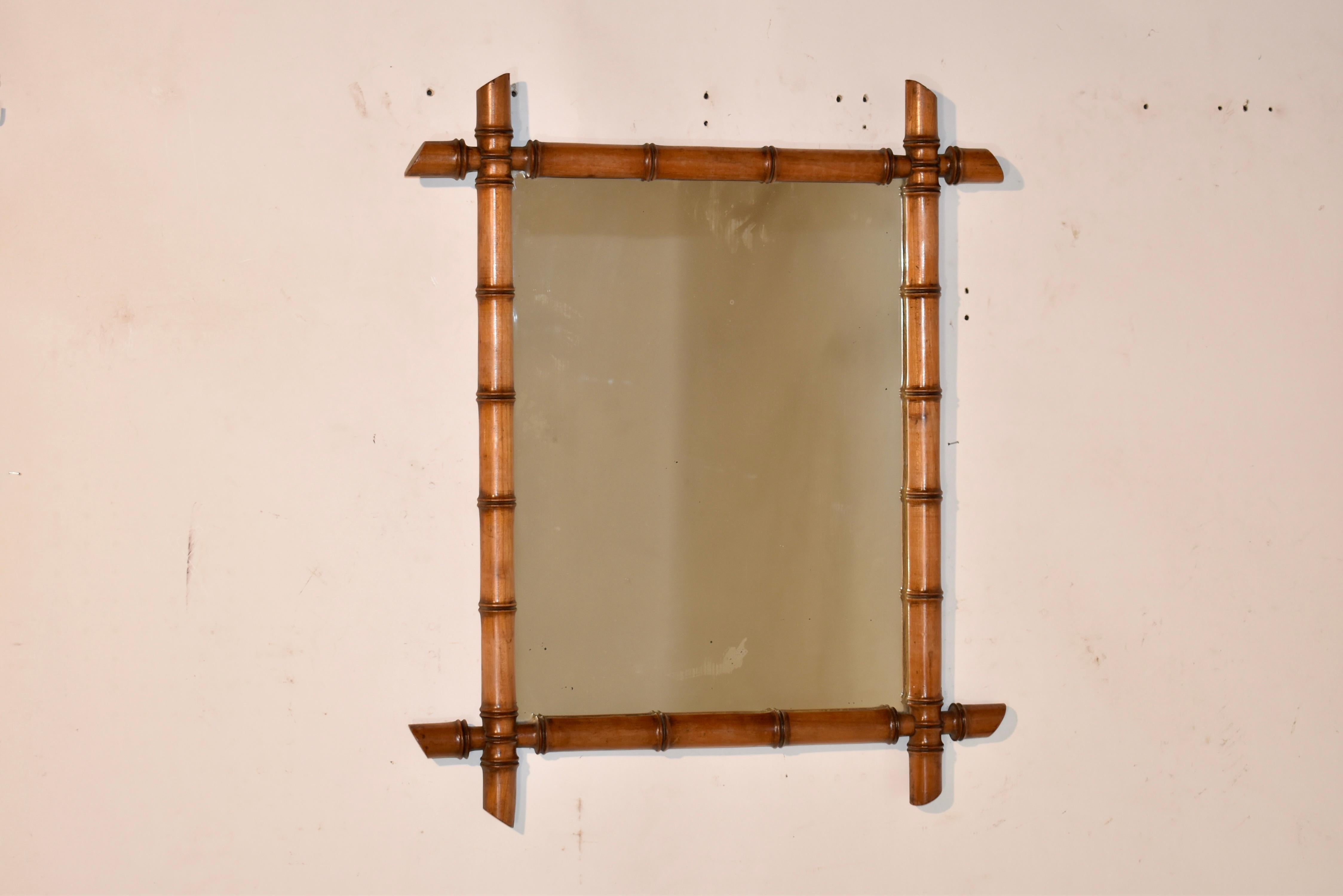 Miroir à encadrement en faux bambou de la fin du 19e siècle, originaire de France.  Le cadre est en cerisier et tourné à la main pour ressembler à du bambou.  Il entoure un miroir ancien, dont le mercure a subi quelques pertes dues à l'âge, pour un