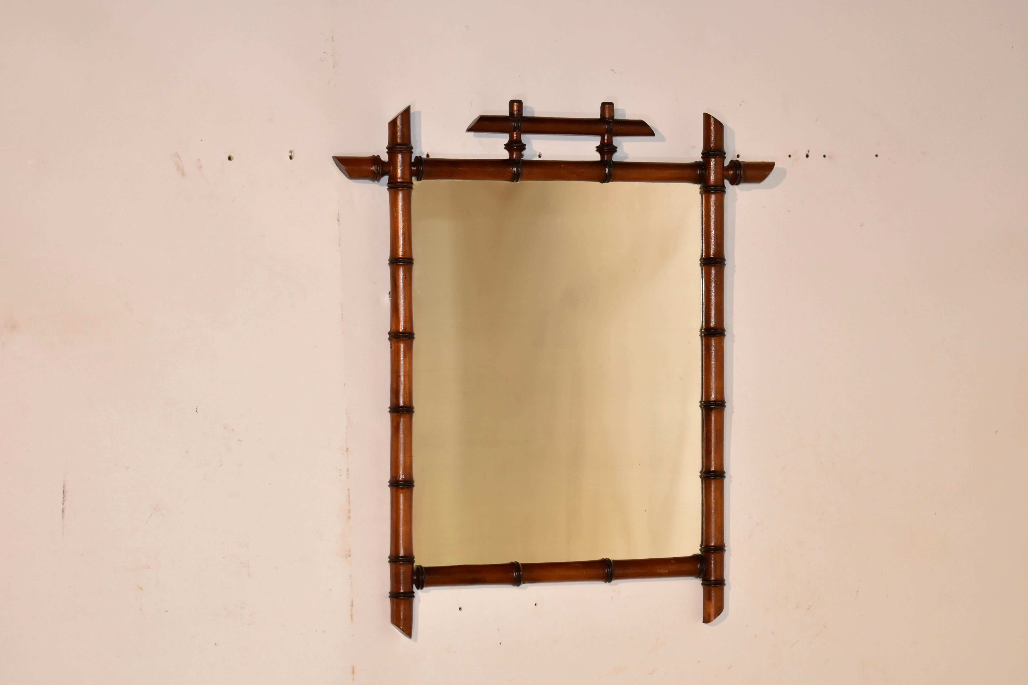 Miroir en faux bambou de la fin du 19e siècle en France.  Le cadre est tourné à la main en cerisier pour donner l'apparence du bambou.  Le cadre entoure un miroir, qui présente une usure honnête due à l'âge et à l'utilisation.