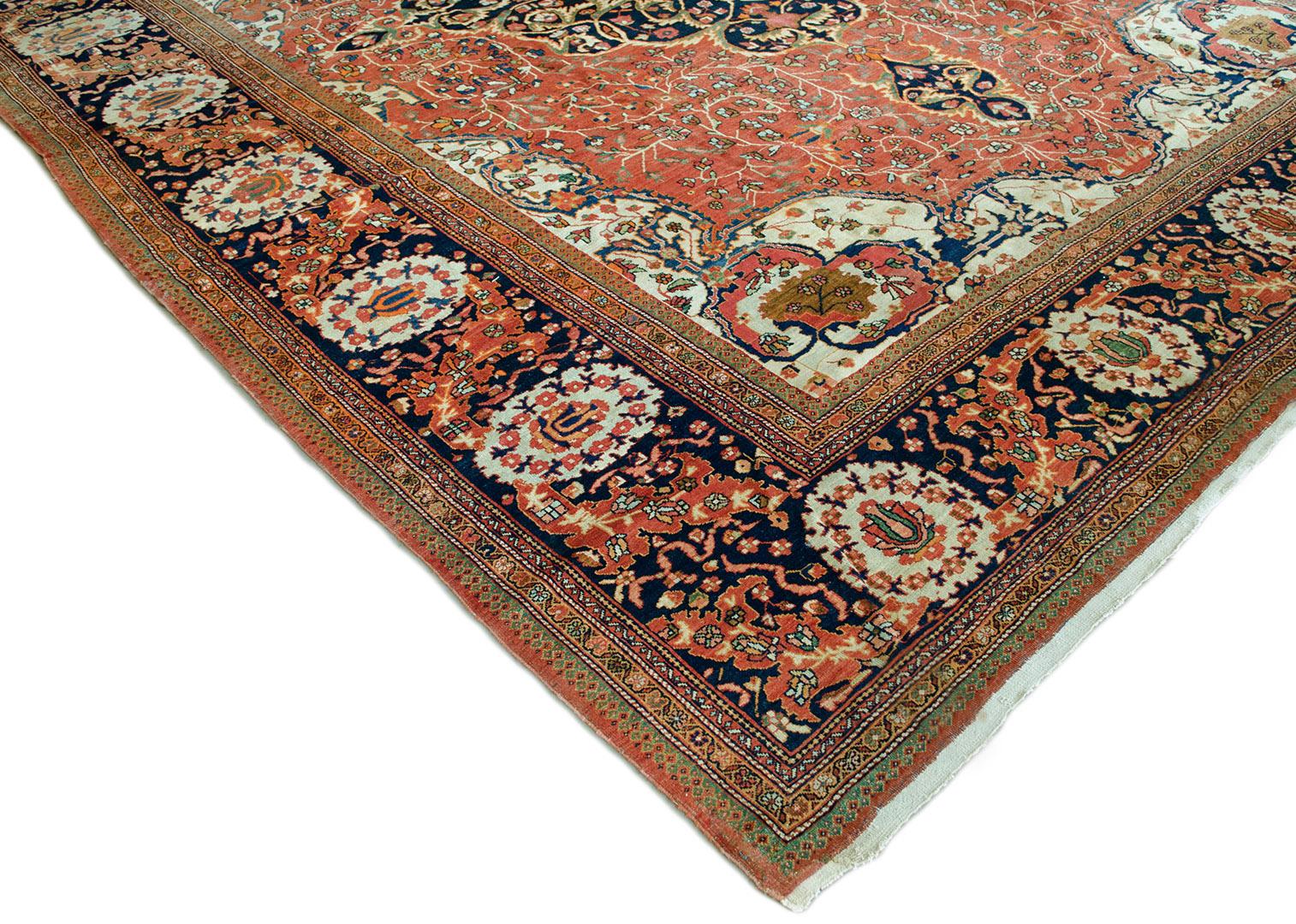 This traditional handwoven Persian Fereghan rug has an extremely fine brick-red field of sparse polychrome floral motifs enclosing a deep indigo and ivory double clasped lozenge medallion, containing a profusion of serrated arabesque ivory-pistachio