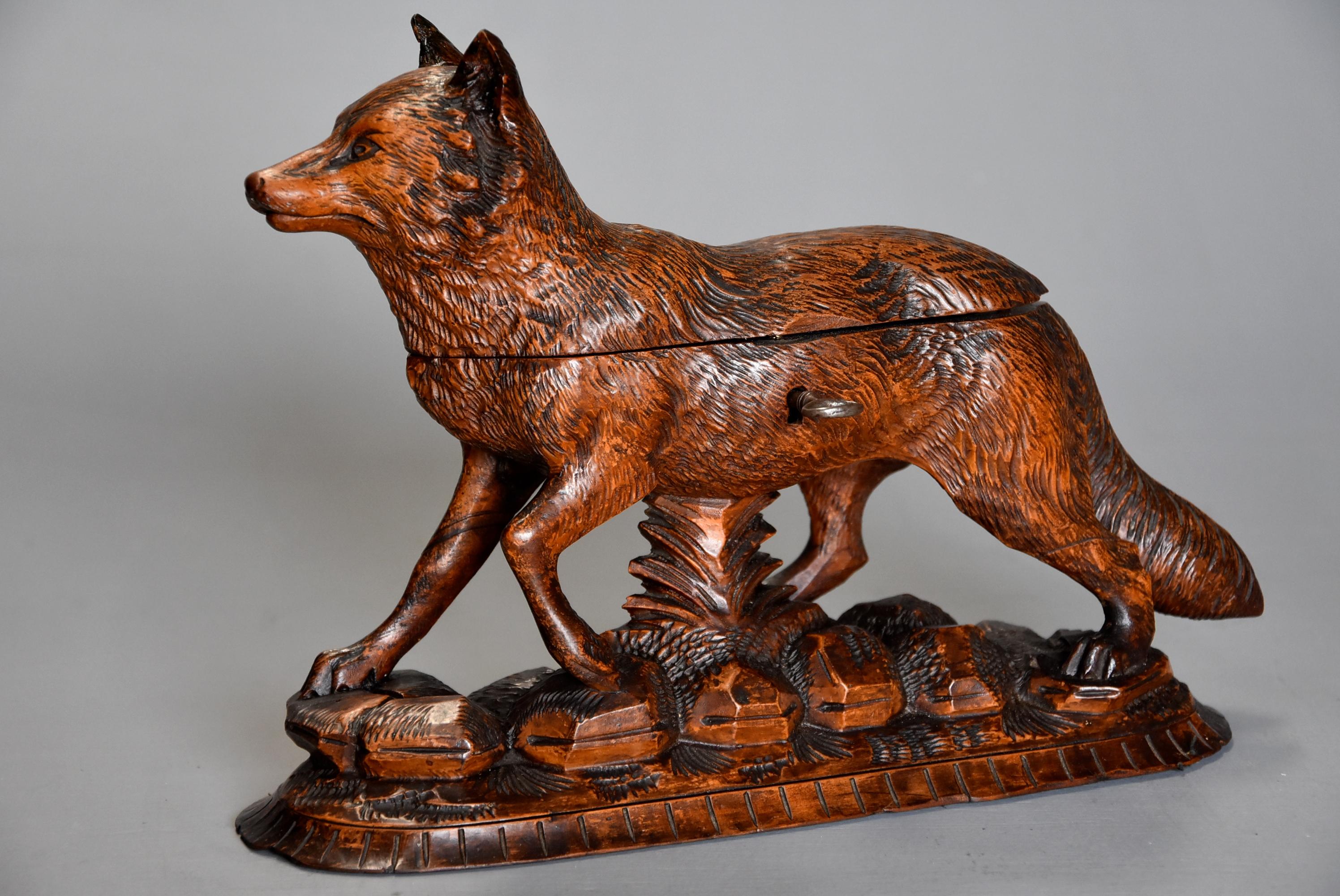 A late 19th century finely carved linden wood Black Forest fox casket, the fine carving typical of the fine work the Brienz area of Switzerland produced.

This superbly carved figure is depicted standing on a naturalistic carved base, the top