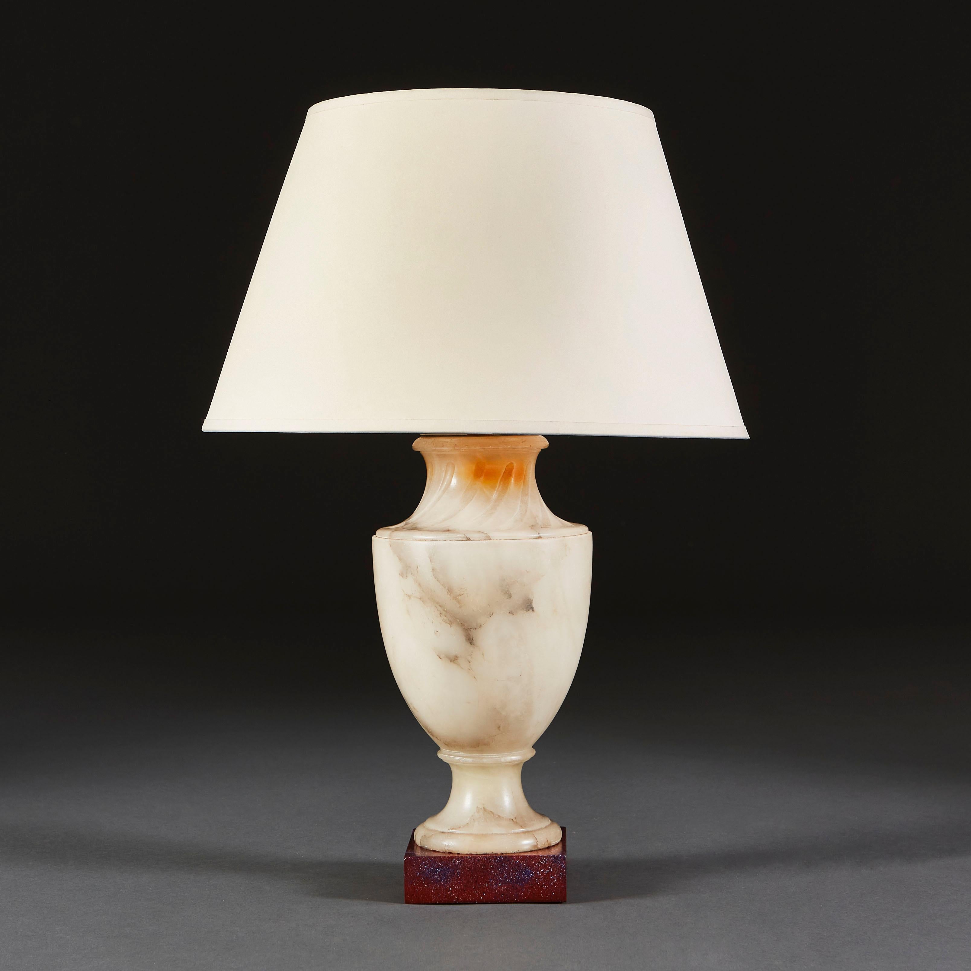 A late nineteenth century French alabaster lamp in the form of an urn, with fluting to the neck, set on a square, ebonised plinth.

Currently wired for the UK. 

Please note: lampshade not included.