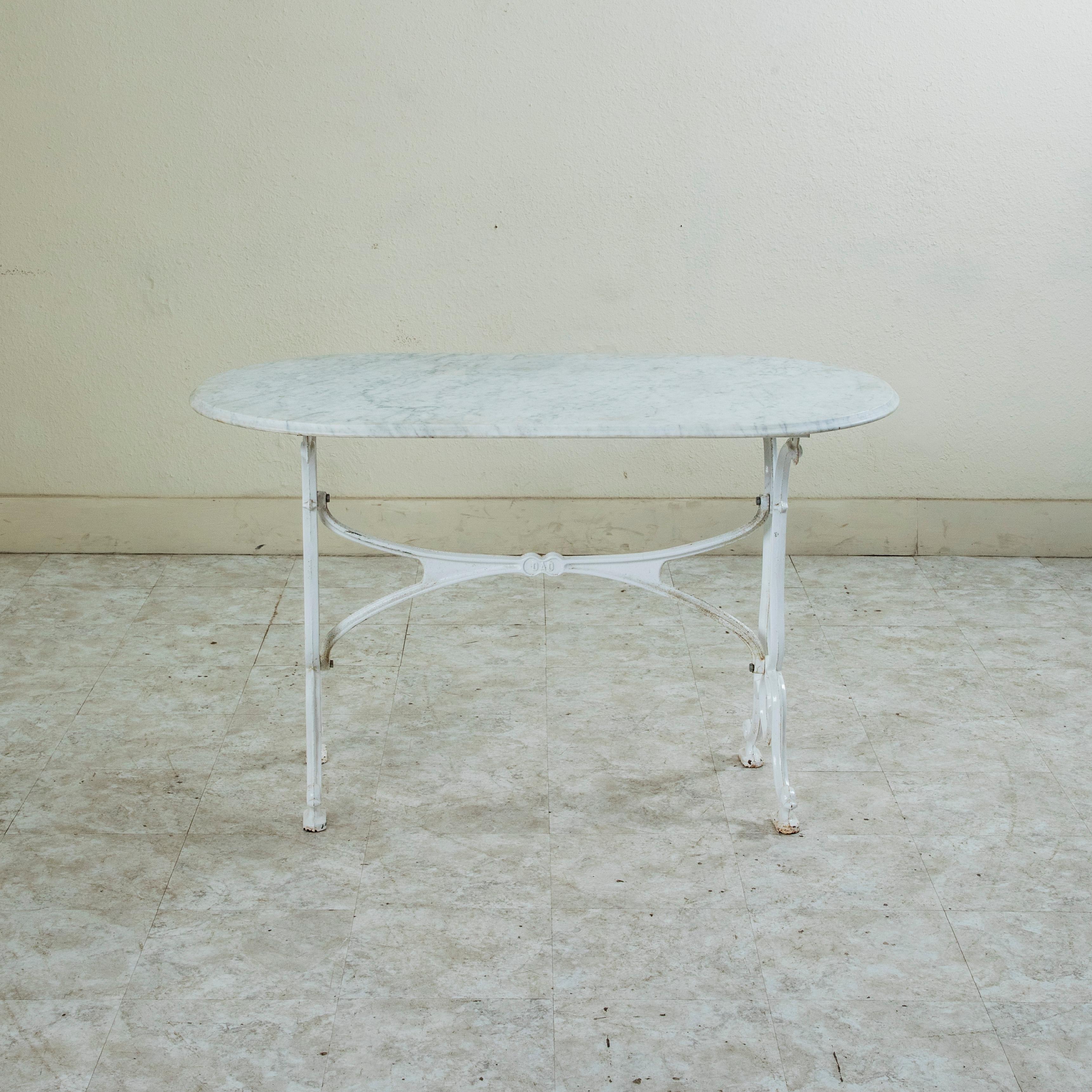 Utilizzato originariamente in una brasserie francese alla fine del XIX secolo, questo tavolo da bistrot o da caffè in ghisa smaltata bianca presenta un solido piano in marmo bianco ovale con venature grigie e un bordo smussato. Le gambe in ferro a