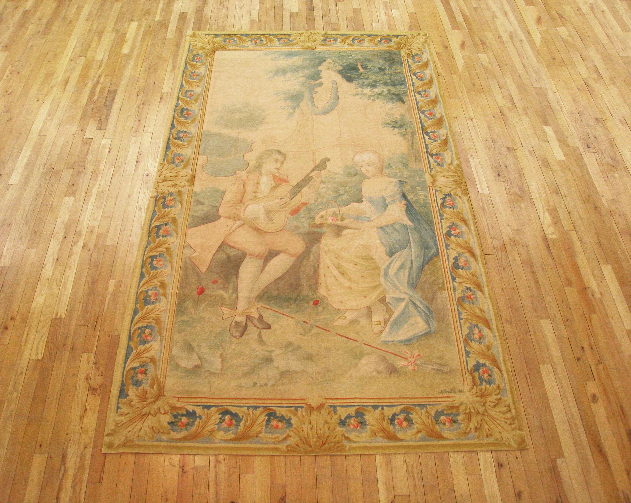 Ein französischer Aubusson-Wandteppich aus dem späten 19. Jahrhundert, der einen Mann darstellt, der vor einer Frau in einer grünen Umgebung musiziert. Eingefasst von einem eleganten Rahmen aus Akanthusblättern. Wolle. Maße: 9'5 