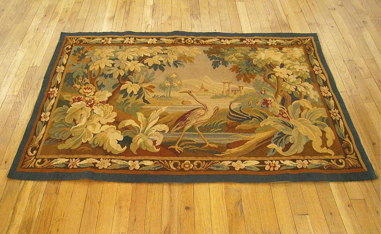 A French Aubusson verdure landscape tapestry from the late 19th century, circa 1890, with a verdant landscape featuring a crane at center between large acanthus plants and trees in the foreground, streams in the middle ground, and a villagescape