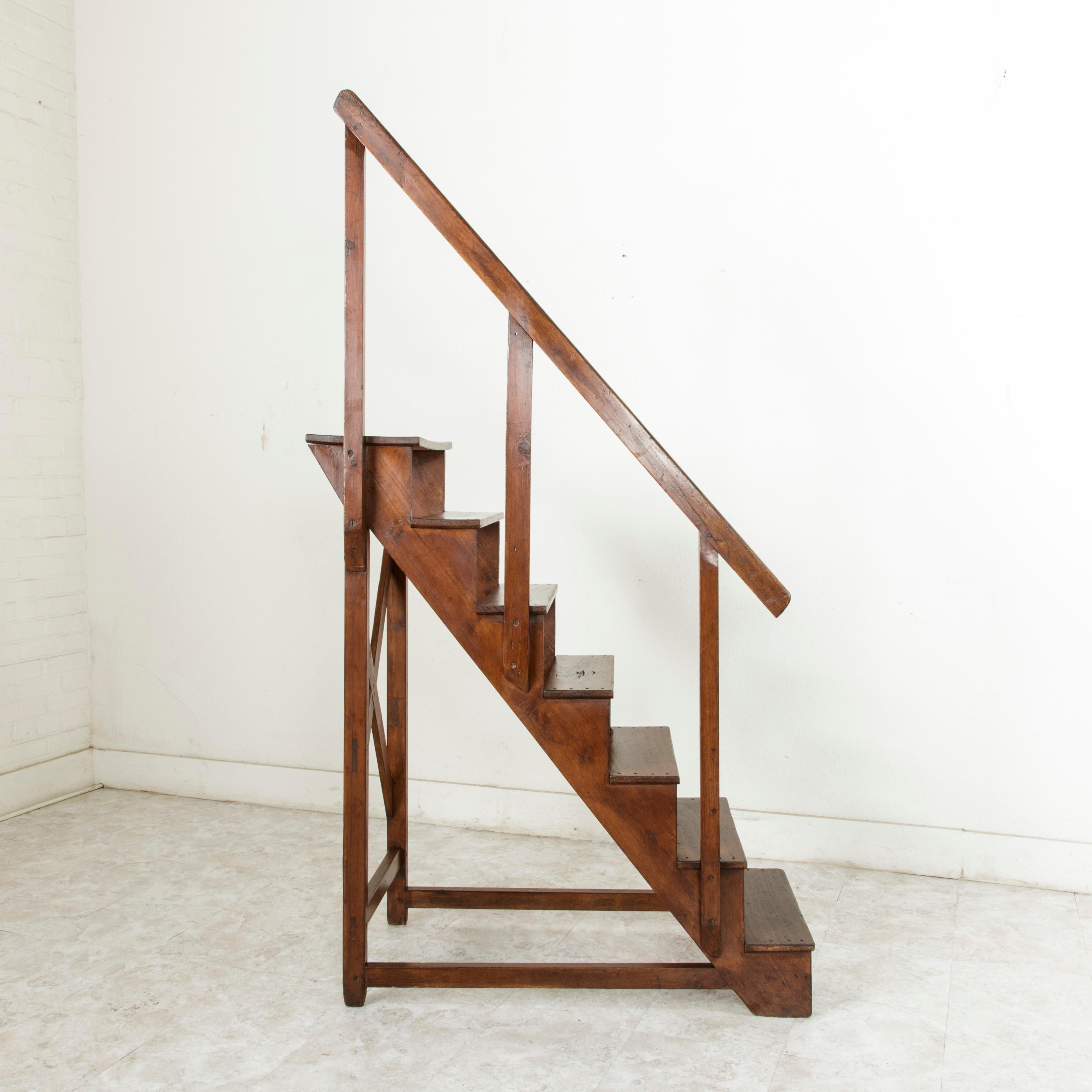 This handsome hand pegged French library ladder from the late nineteenth century is constructed of beech wood and features a hand rail on the left side, providing stability when climbing for hard-to-reach books. With seven steps that could also act