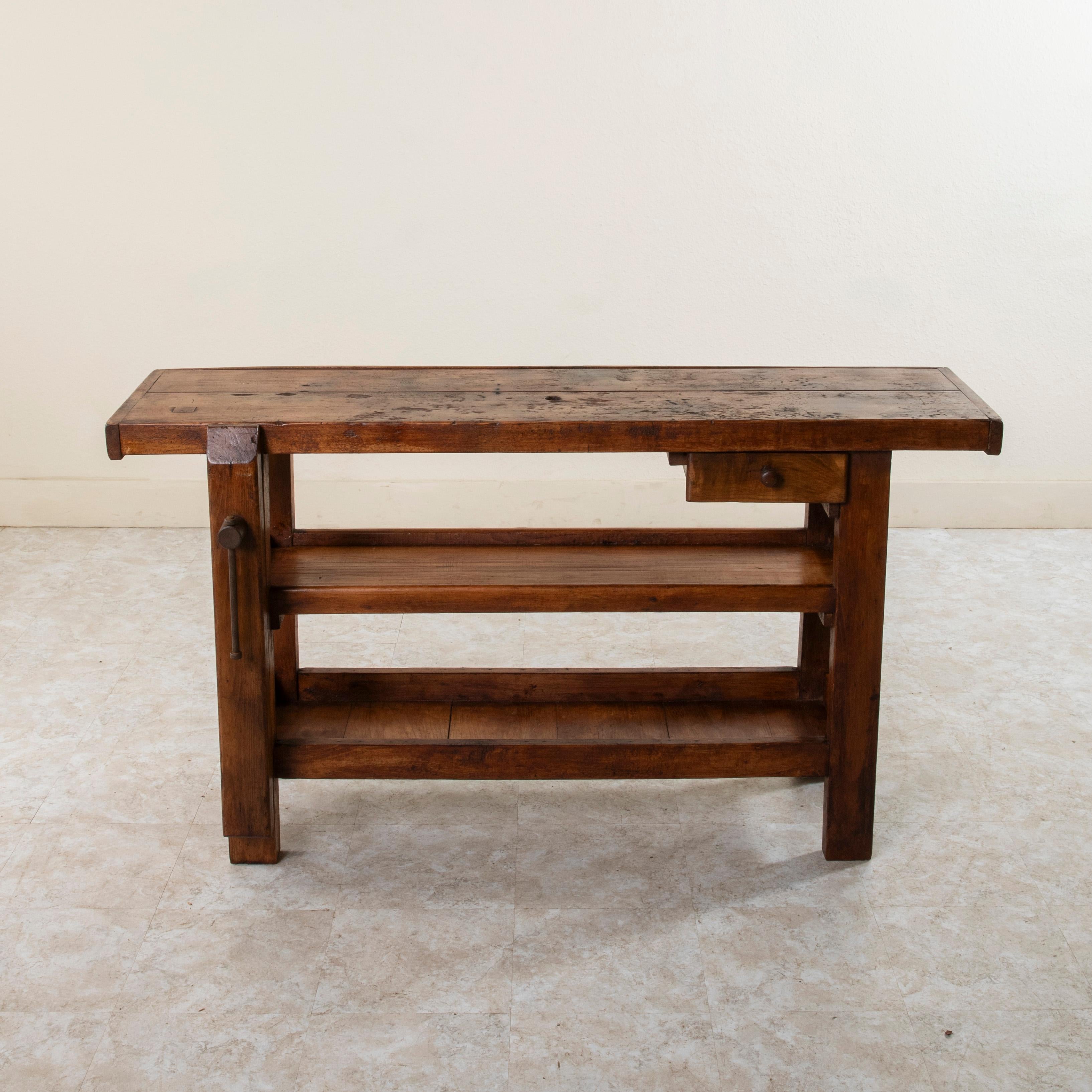 This late nineteenth century beechwood and oak workbench from Normandy, France, features two slots at the back of its two inch thick top once used to store the artisan's tools close at hand. Its single drawer and two lower shelves provide ample