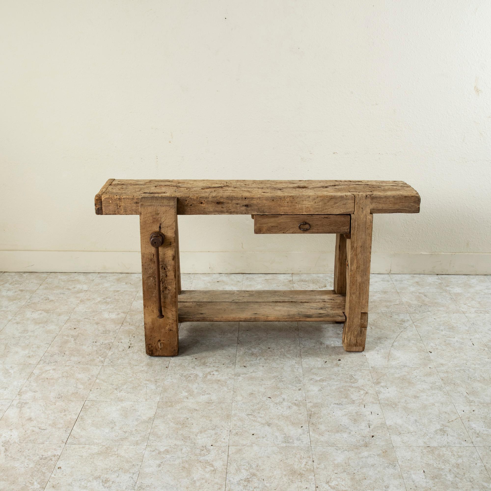 This late nineteenth century French bleached oak workbench features a vise grip on the left side that can be positioned so that a bar towel can be hung from it. A drawer on the right where tools would have been kept now serves as extra storage. The