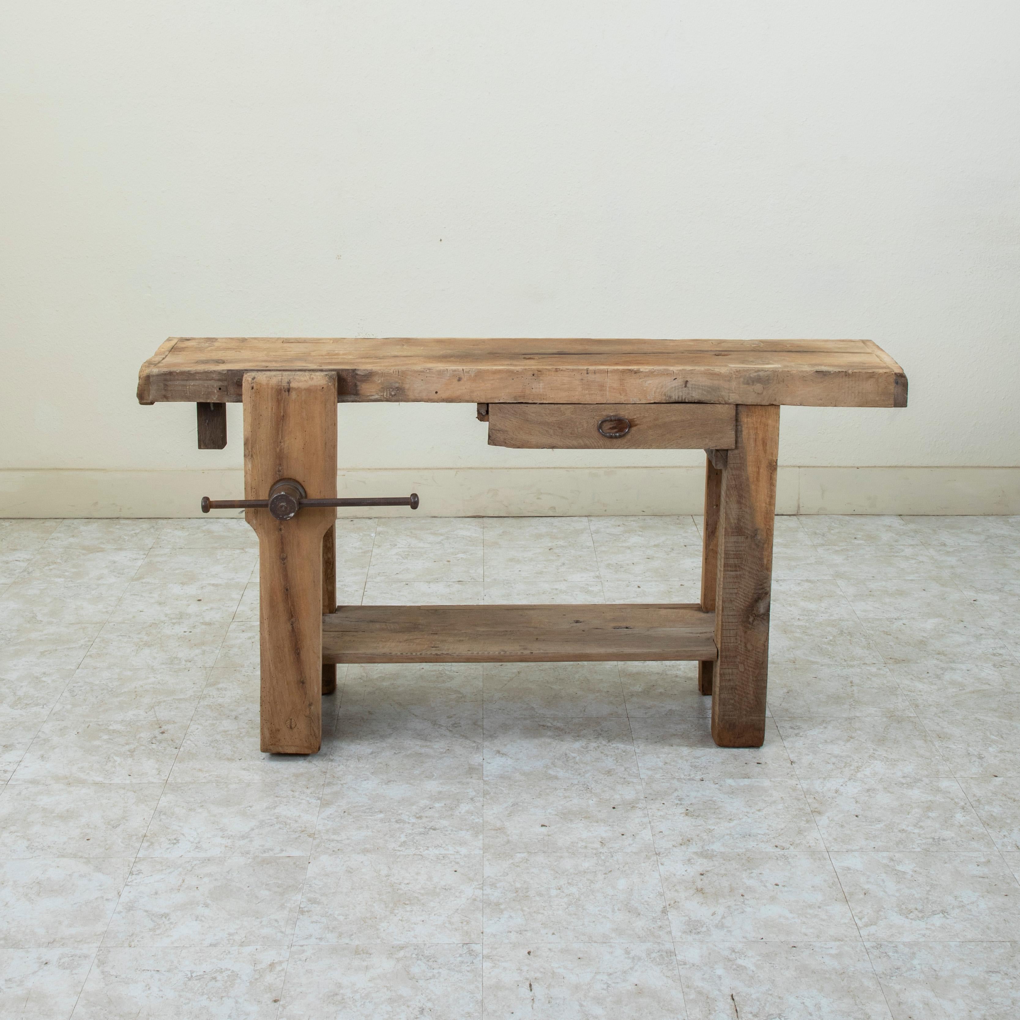 This late nineteenth century French bleached oak workbench features a vise grip on the left side that can be positioned so that a bar towel can be hung from it. A drawer on the right where tools would have been kept now serves as extra storage. The