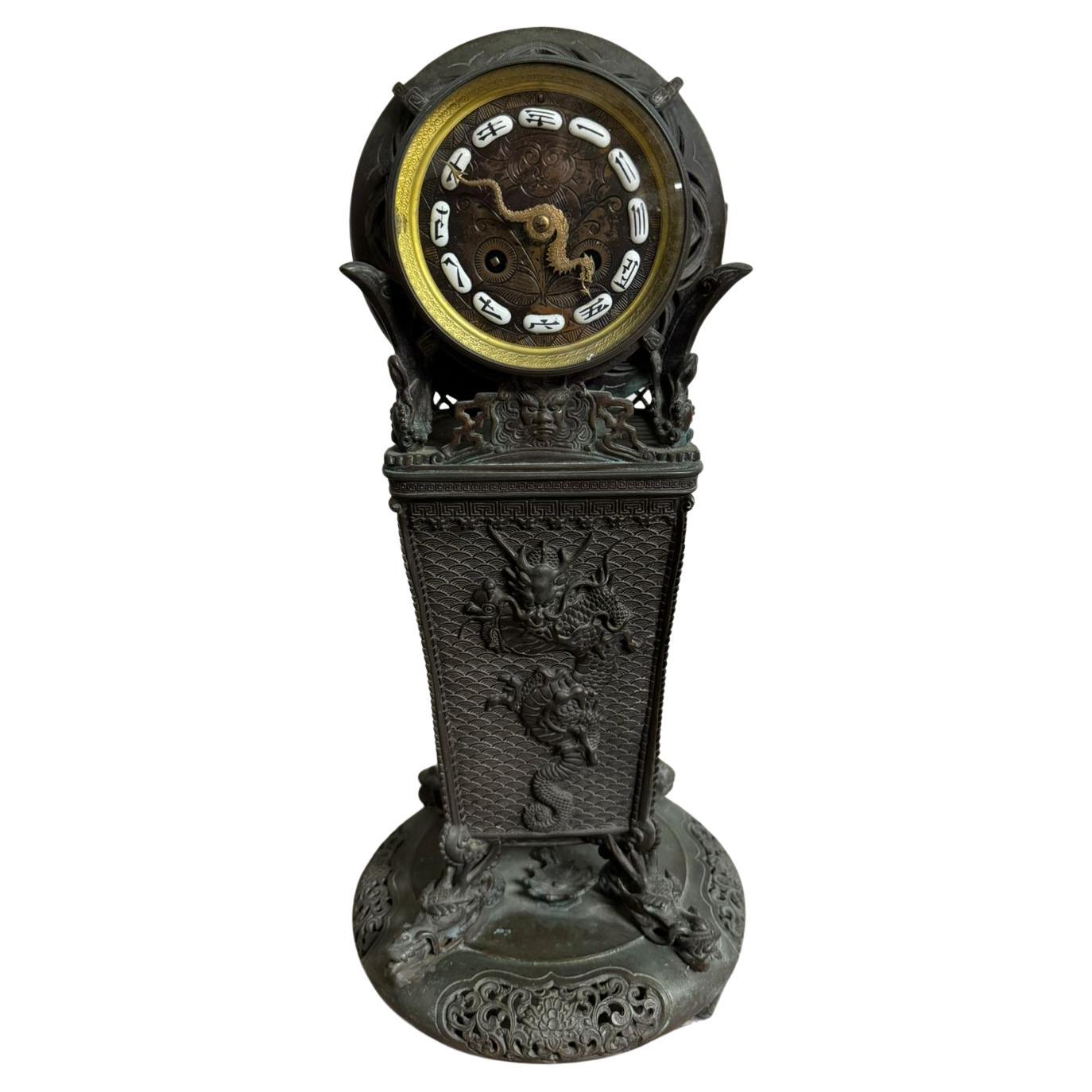 A stunning French bronze clock with Oriental influences, crafted circa 1900. This exceptional piece features a black patina finish, elegantly contrasted by gilded bronze hands shaped like dragons. The intricate decorations include dragons and