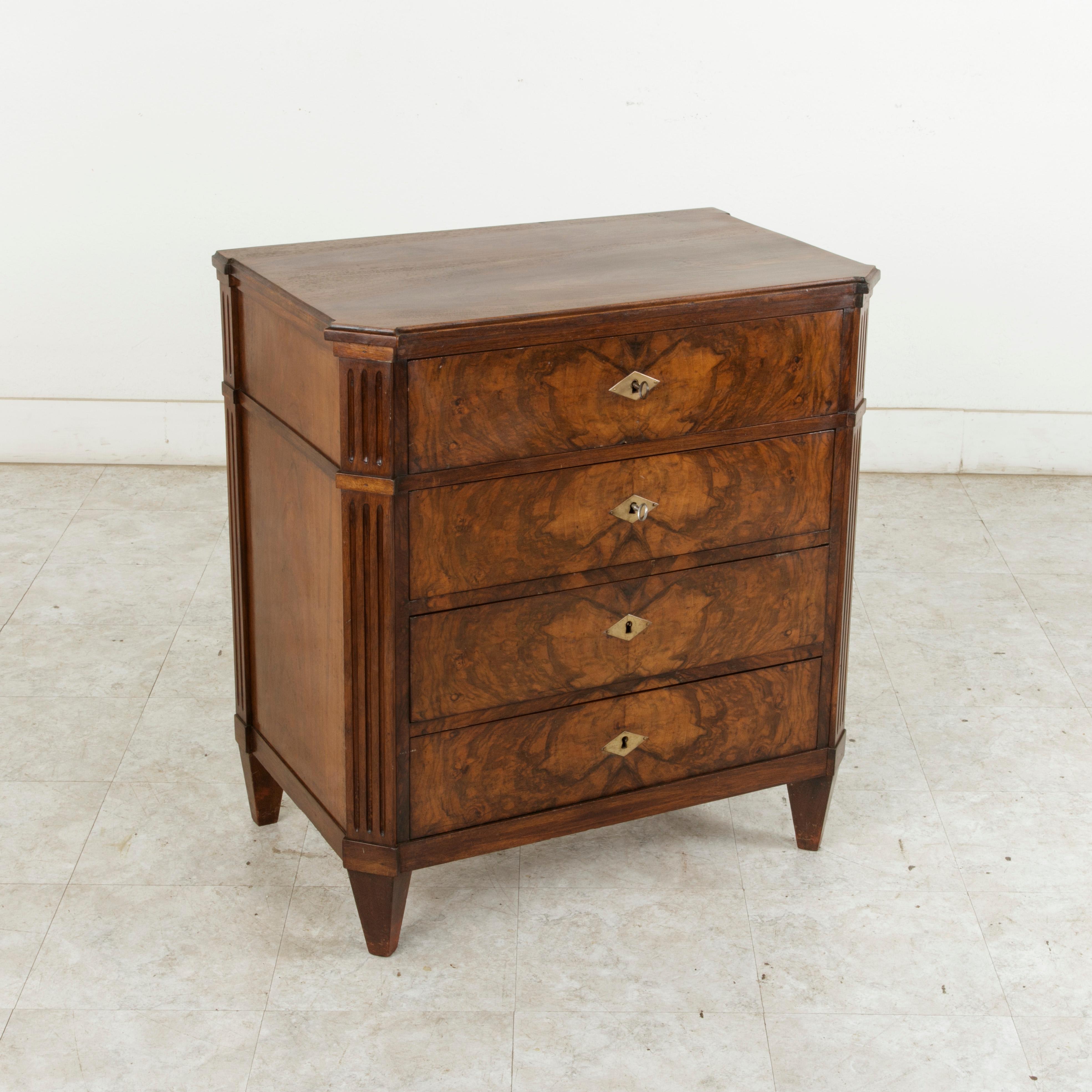 This French commode or chest from the late 19th century features a mix of French furniture styles. Its beautiful bookmatched burl walnut facade is reminiscent of the Louis Philippe style, while its fluted corners and tapered square legs recall the