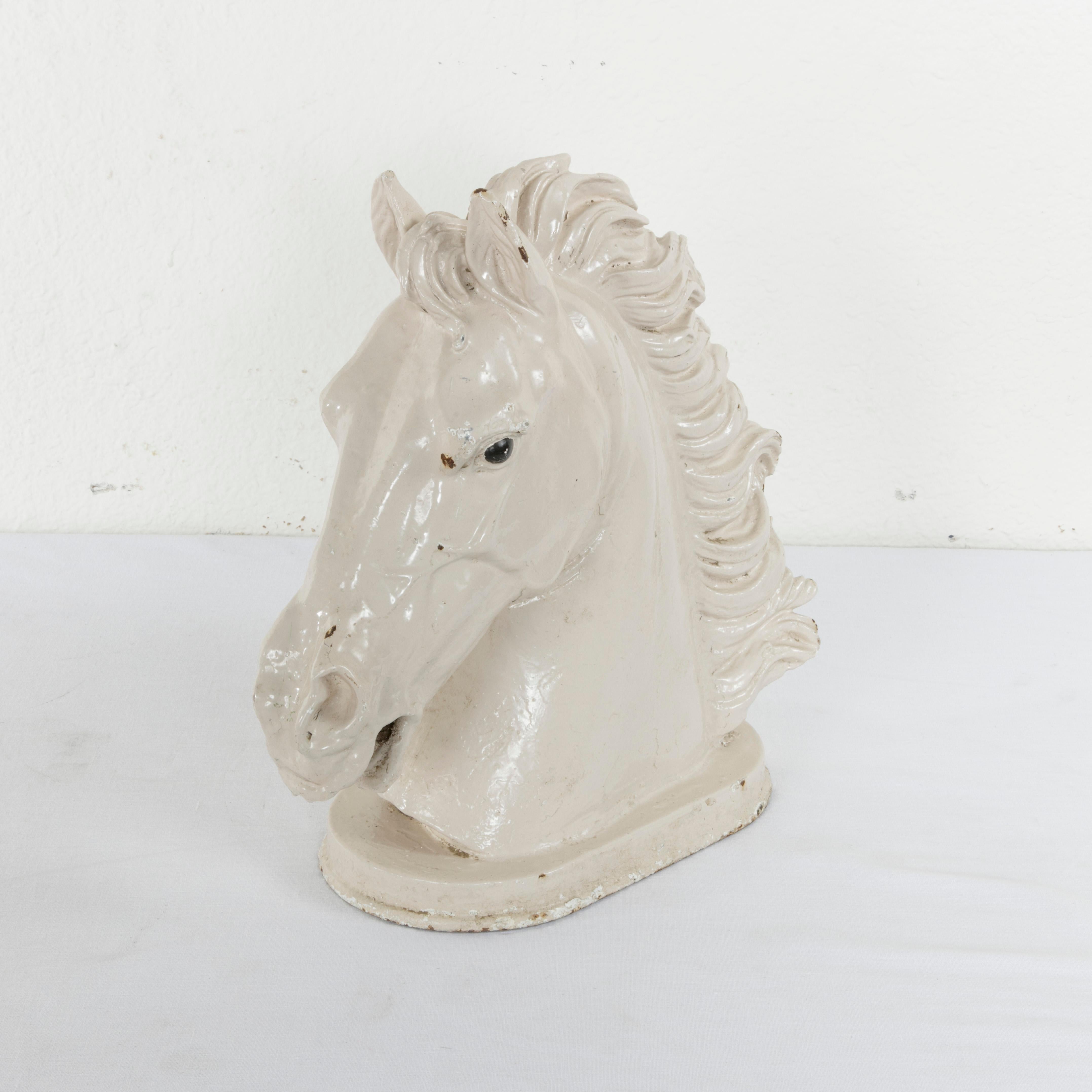 This late 19th century French cast iron bust features a horse's head with a magnificent mane. Originally mounted outside of a butcher shop that sold horse meat, this piece is enameled white, and the eyes are detailed in black. Standing at nearly 15