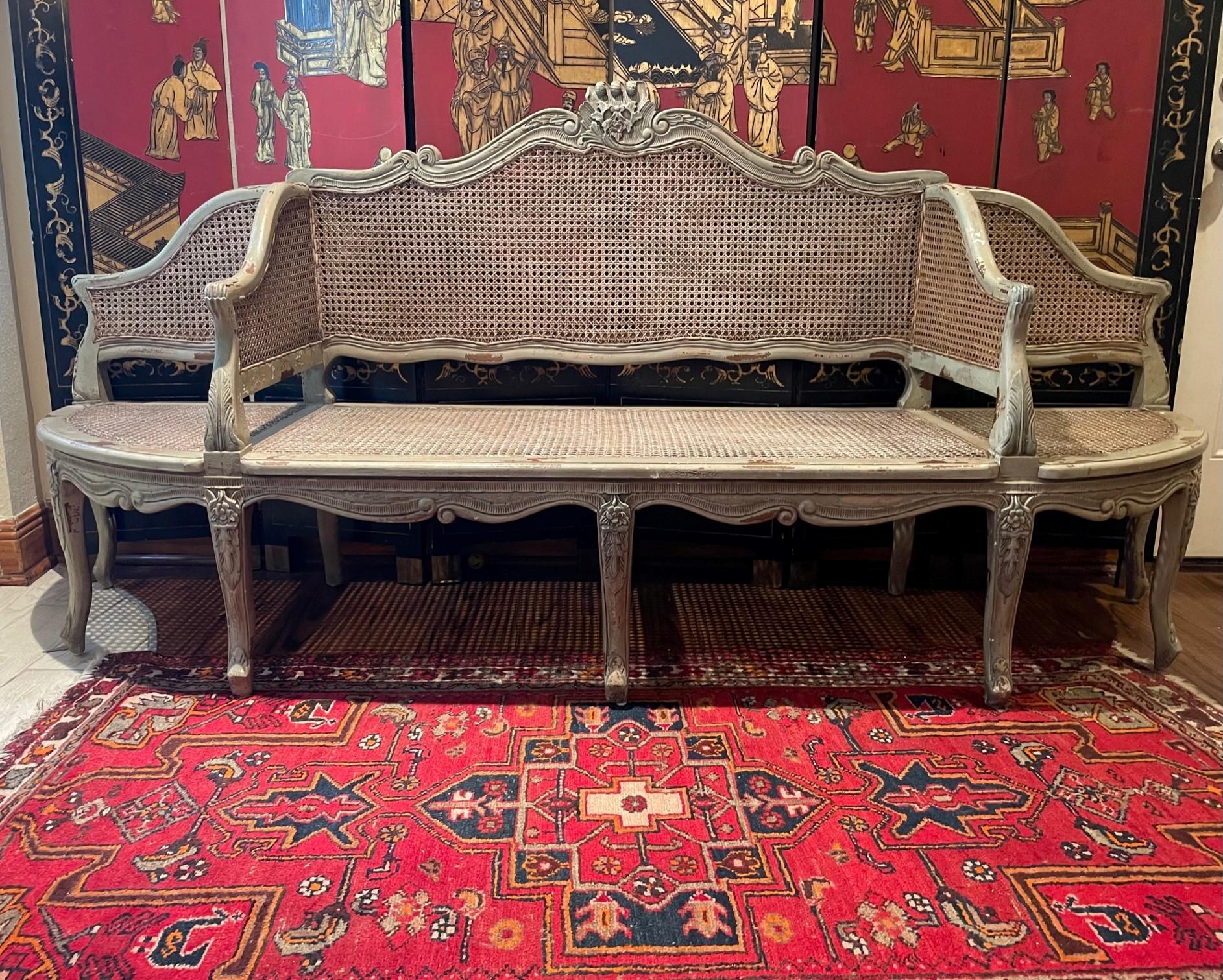 Late 19th century French caned sofa, canape a confidents.

Large movable -canape a confidents- seat, curving and counter-curving with floral motif carvings. It is designed in the style after Jean Baptiste Boulard, circa 1775, and represents all