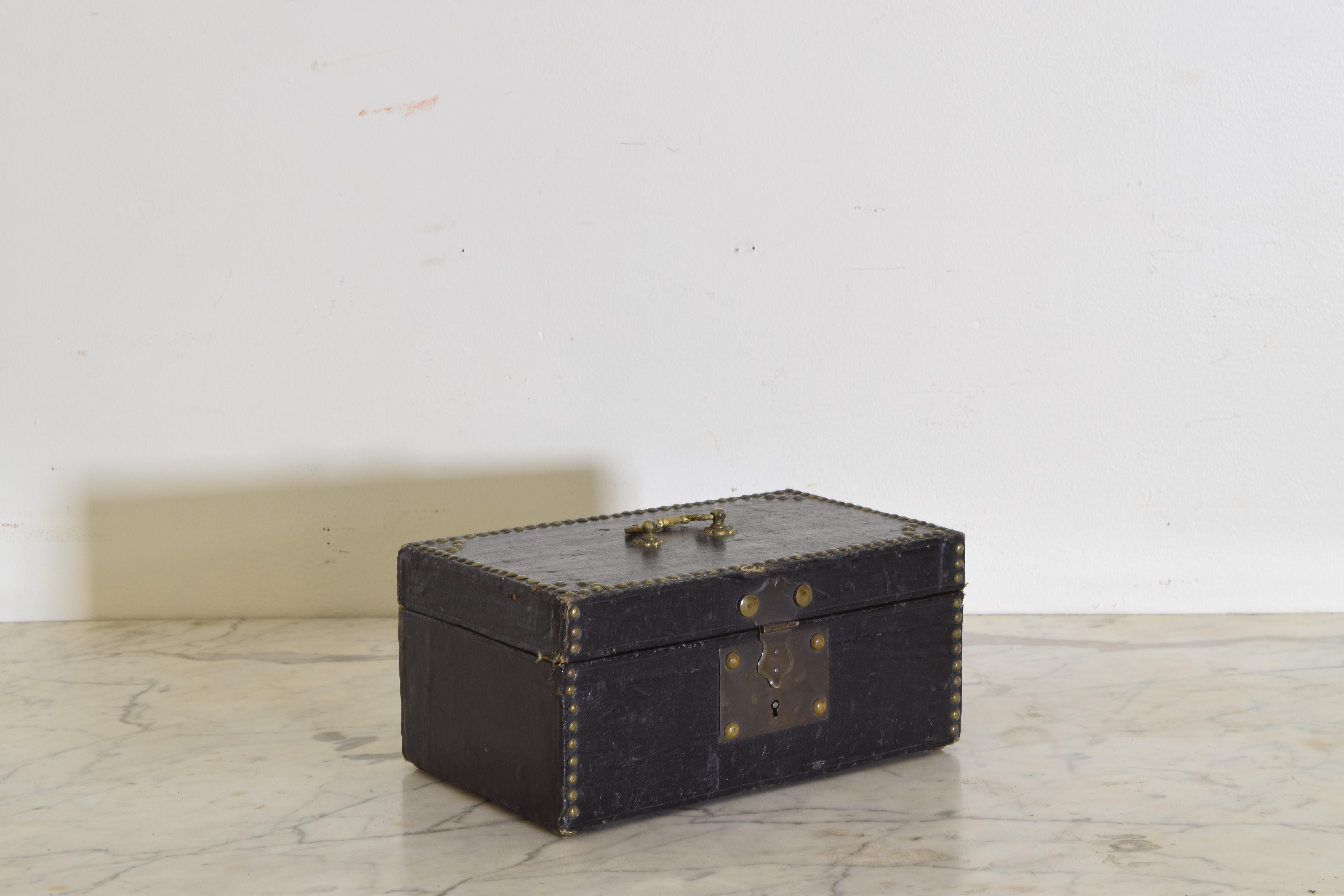 A coated canvas-covered box with nail head decoration, brass lock and brass handle.