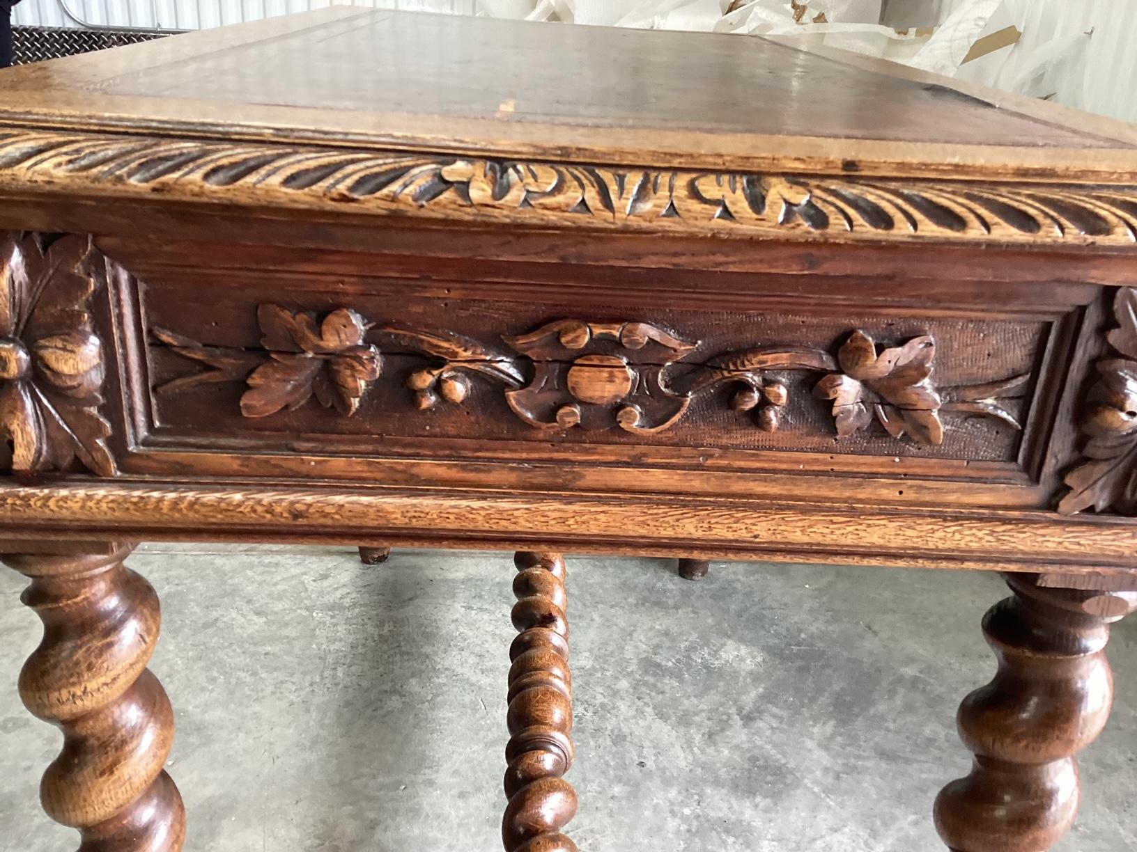 This is an authentic French antique carved desk with a leather top made of oak, having intricate carving on all sides and the barley twist legs. There is a leather top which shows signs of age in the color, but it is not damaged. As you can see in