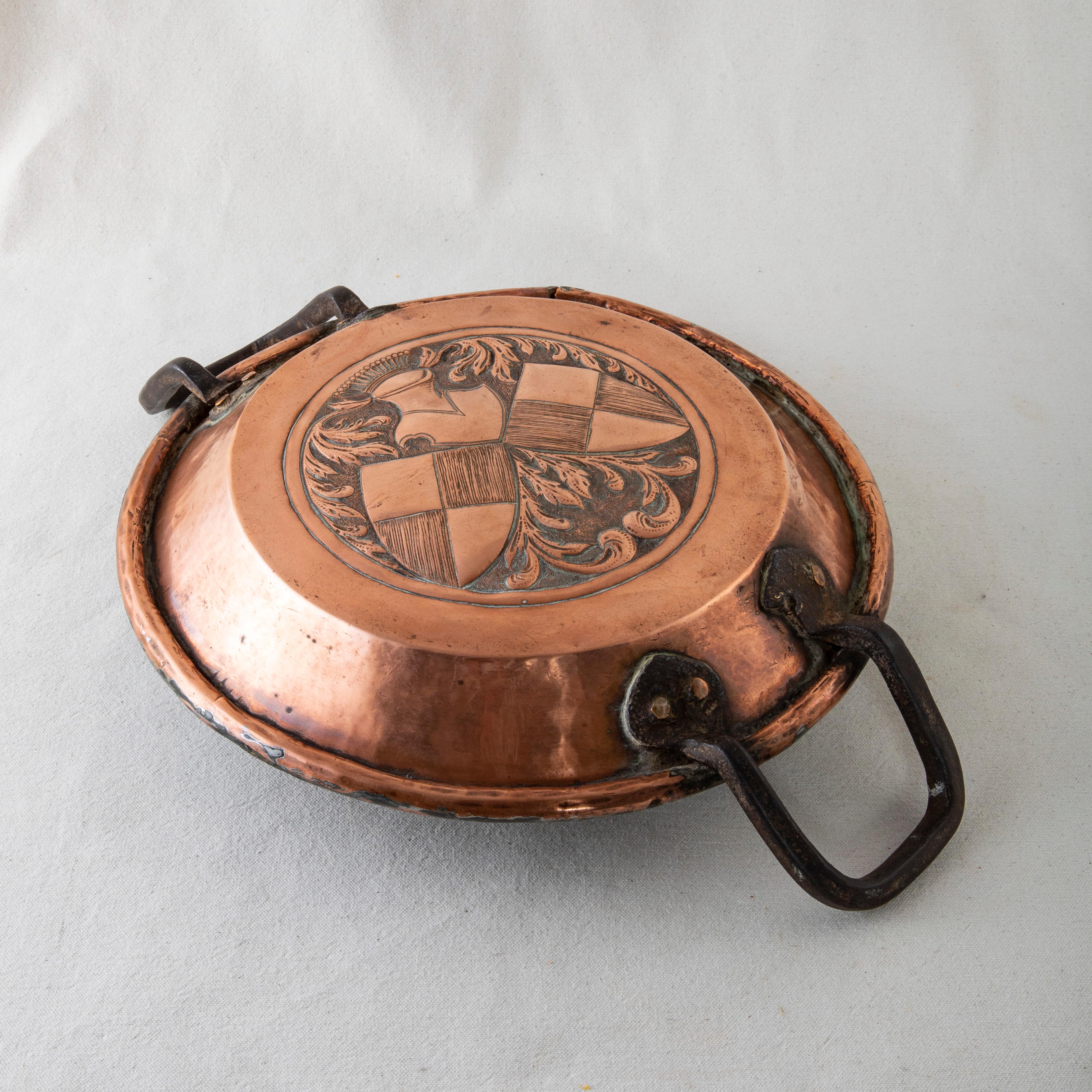 Originally used in the kitchen of a French chateau, this late nineteenth century copper repousse tart pan features a crowned frogmouth helmet above two quartered shields. The helmet and shields are surrounded by scrolling leaves. The pan is fitted
