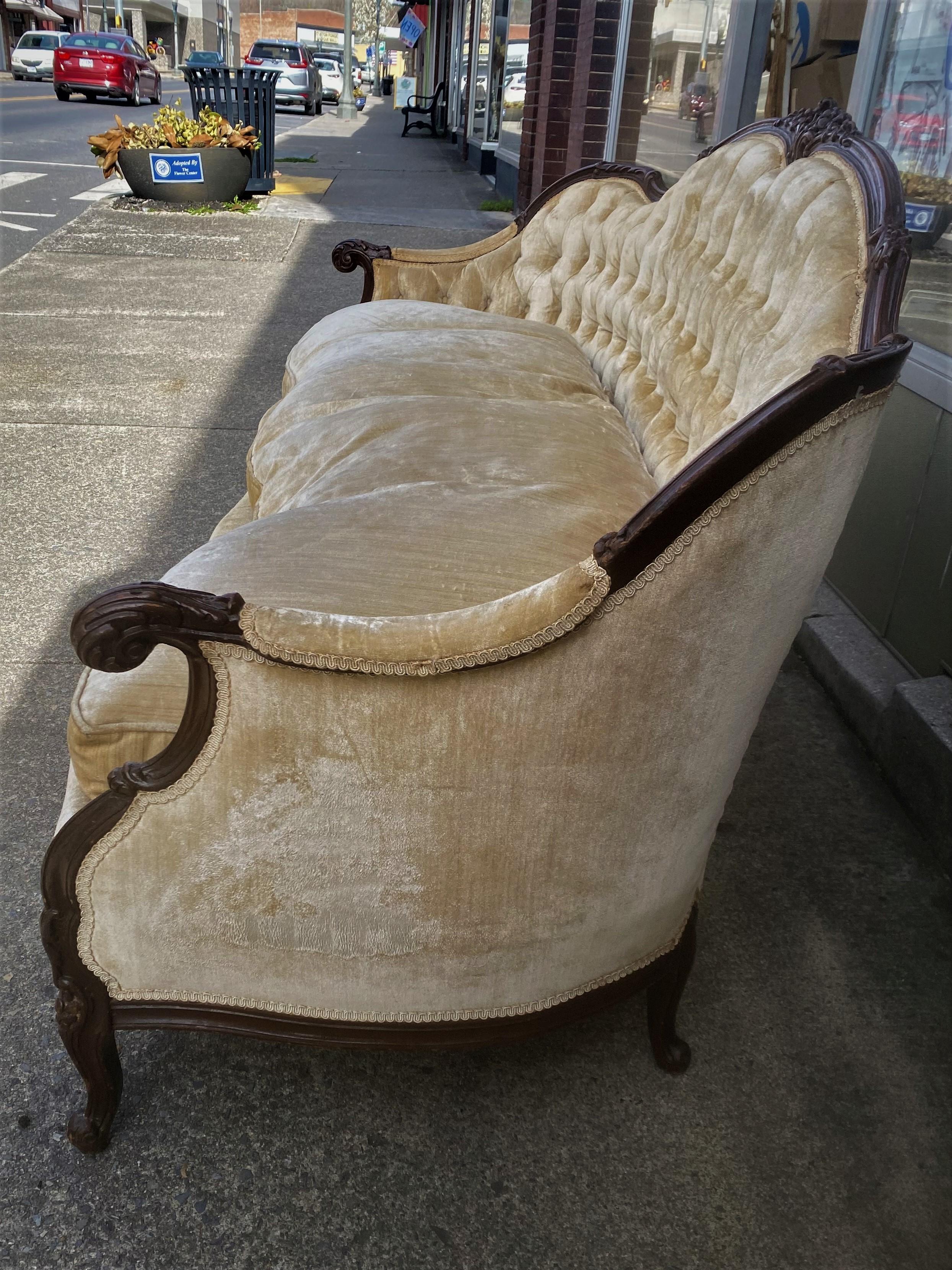 This is a lovely settee with carved dark wood framing the pale beige velvet upholstery and down cushions. Although the upholstery is warm and comfy, it is not in perfect shape, it has creases, stains from furniture stain and a small tear. Someone