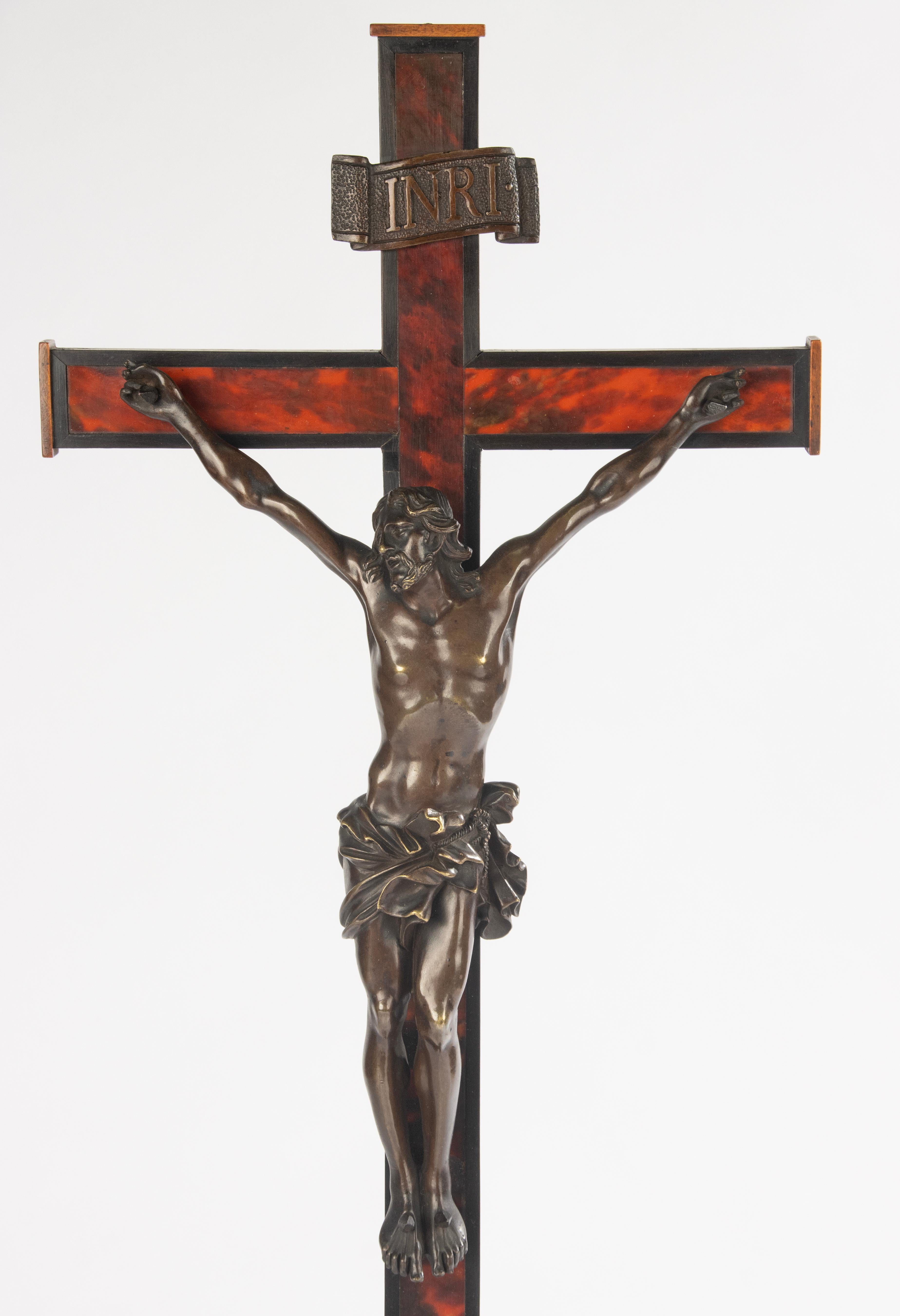 Un crucifix français raffiné de la fin du 19e siècle.
La croix est fabriquée en bois magnifiquement poli, plaqué en fausse écaille de tortue, créant un effet chaleureux et élégant. Montée sur une base octogonale étagée, la pièce a une forte présence