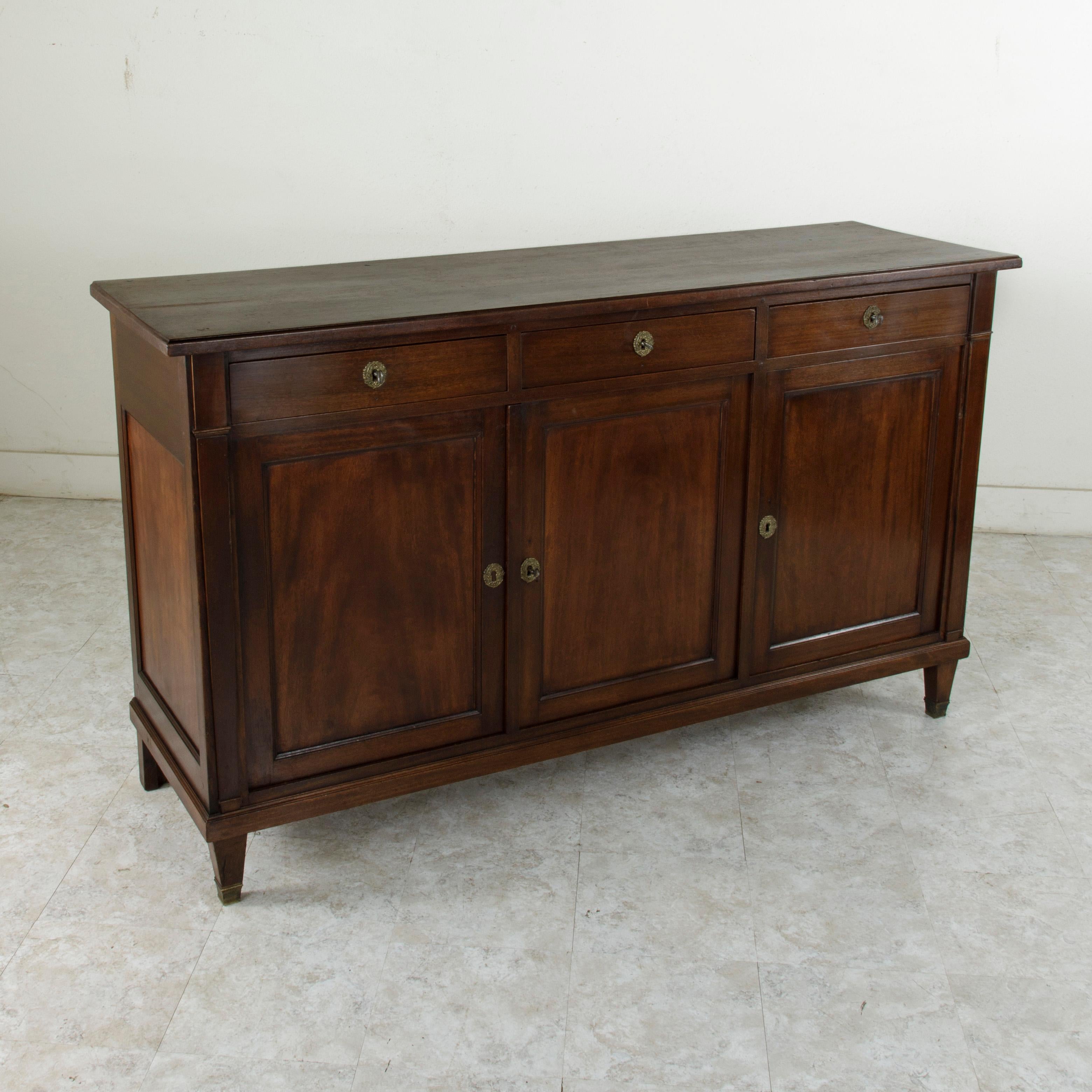 This late 19th century French Directoire style enfilade or sideboard is constructed of mahogany and features a beveled top and hand pegged paneled sides and doors. Three drawers of dovetail construction fit into the apron below the top and are