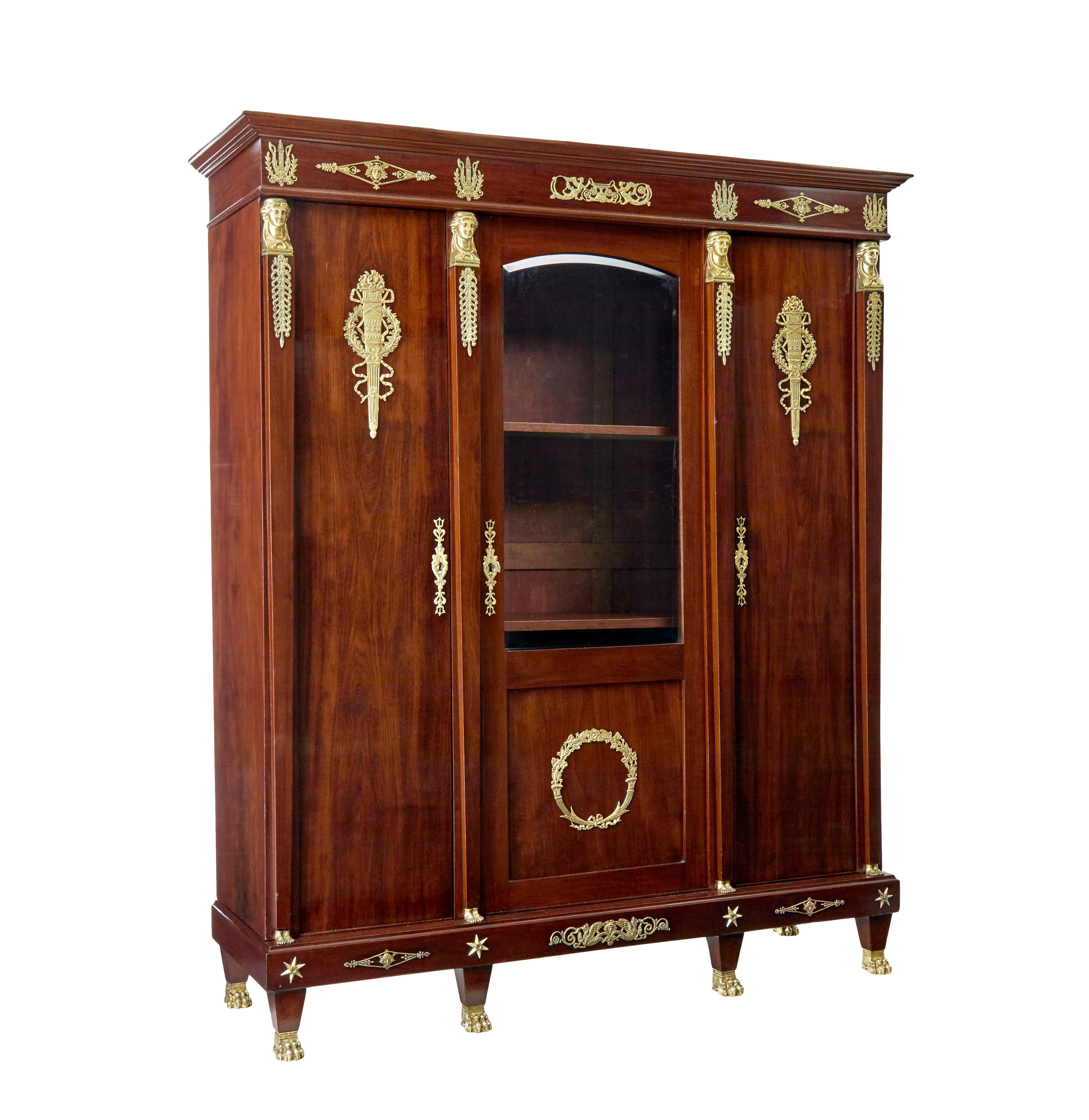 Fine quality french empire revival mahogany cabinet circa 1890.

Generous proportions and as with all furniture of this scale and period it was built to come apart.

Central glazed door with ormolu wreath mount, flanked either side by a single door