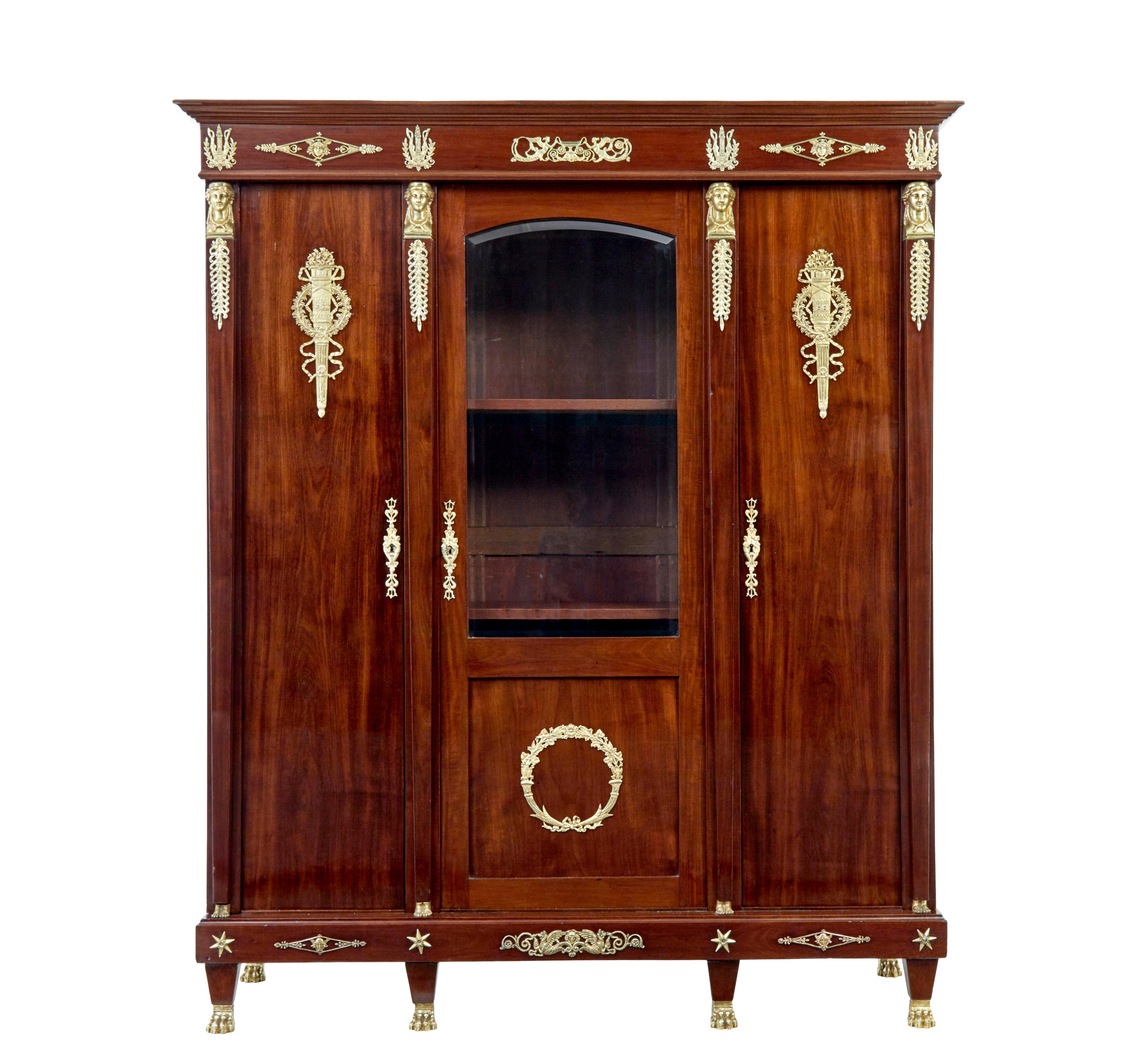 Fine quality french empire revival mahogany cabinet circa 1890.

Generous proportions and as with all furniture of this scale and period it was built to come apart.

Central glazed door with ormolu wreath mount, flanked either side by a single door