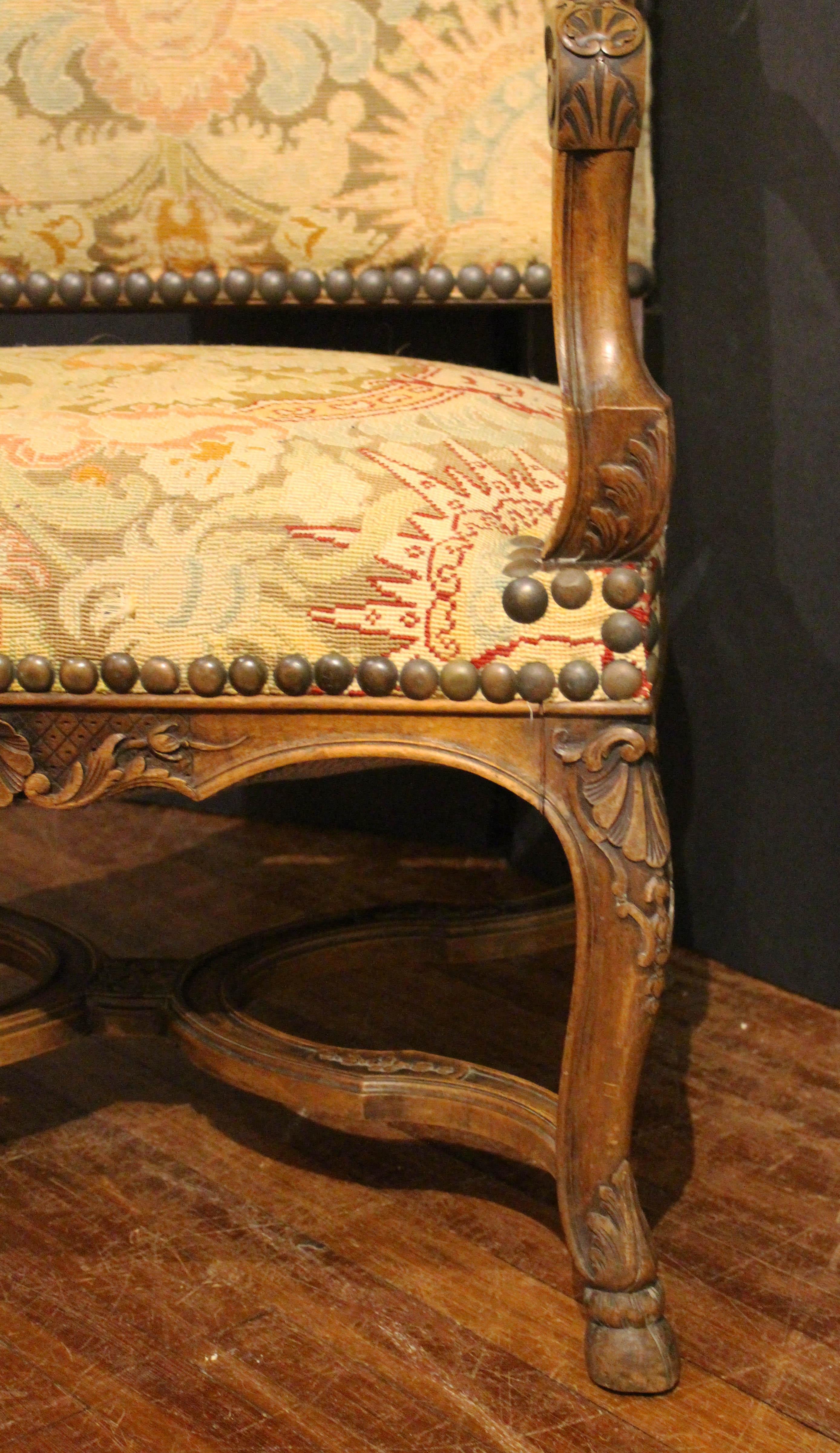 Late 19th century Regence style fauteuil, French. Well carved walnut. Shaped cross stretcher. Shell & acanthus carving throughout. Cabriole legs ending in hoof feet. Original tapestry upholstery with some fading. 26 3/4
