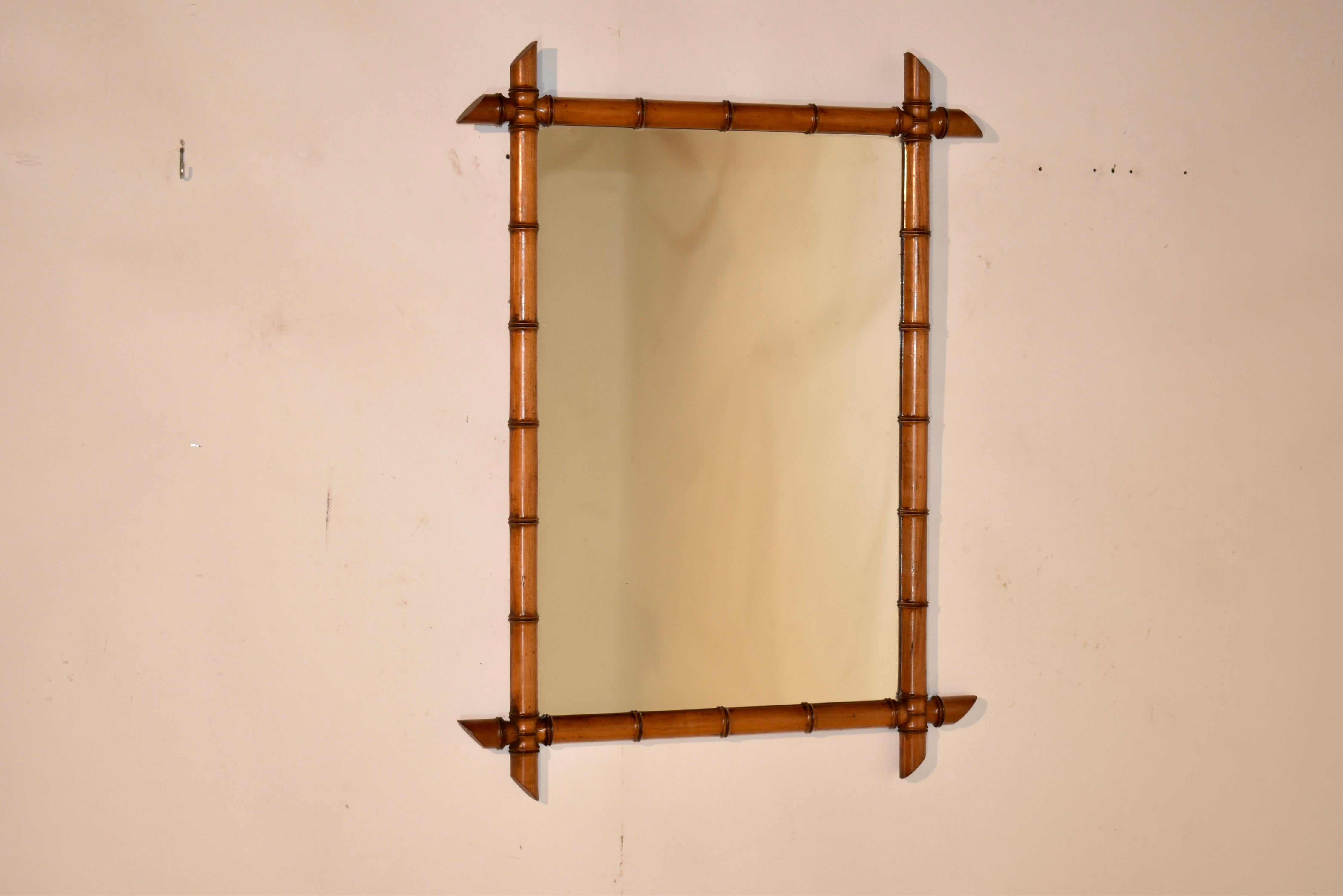 Late 19th century faux bamboo mirror made from cherry in France. The frame is hand turned to have the appearance of bamboo, but is made from rich cherry and retains its original color and patina. The corners of the frame intersect and surround a