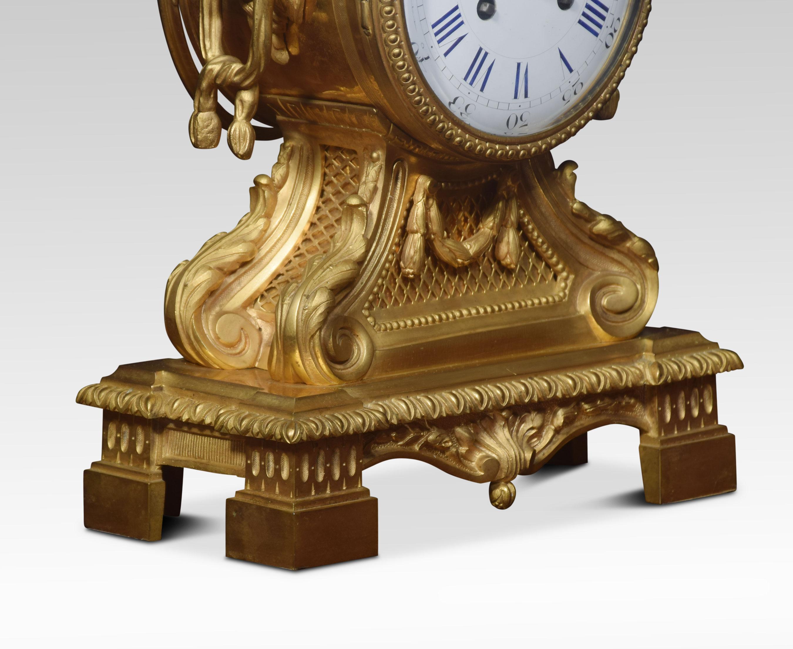 Pendule de cheminée française de la fin du XIXe siècle en métal doré, le boîtier surmonté d'un fleuron en forme d'urne, au-dessus du cadran émaillé à chiffres romains et arabes renfermant le mouvement à deux trains estampillé 