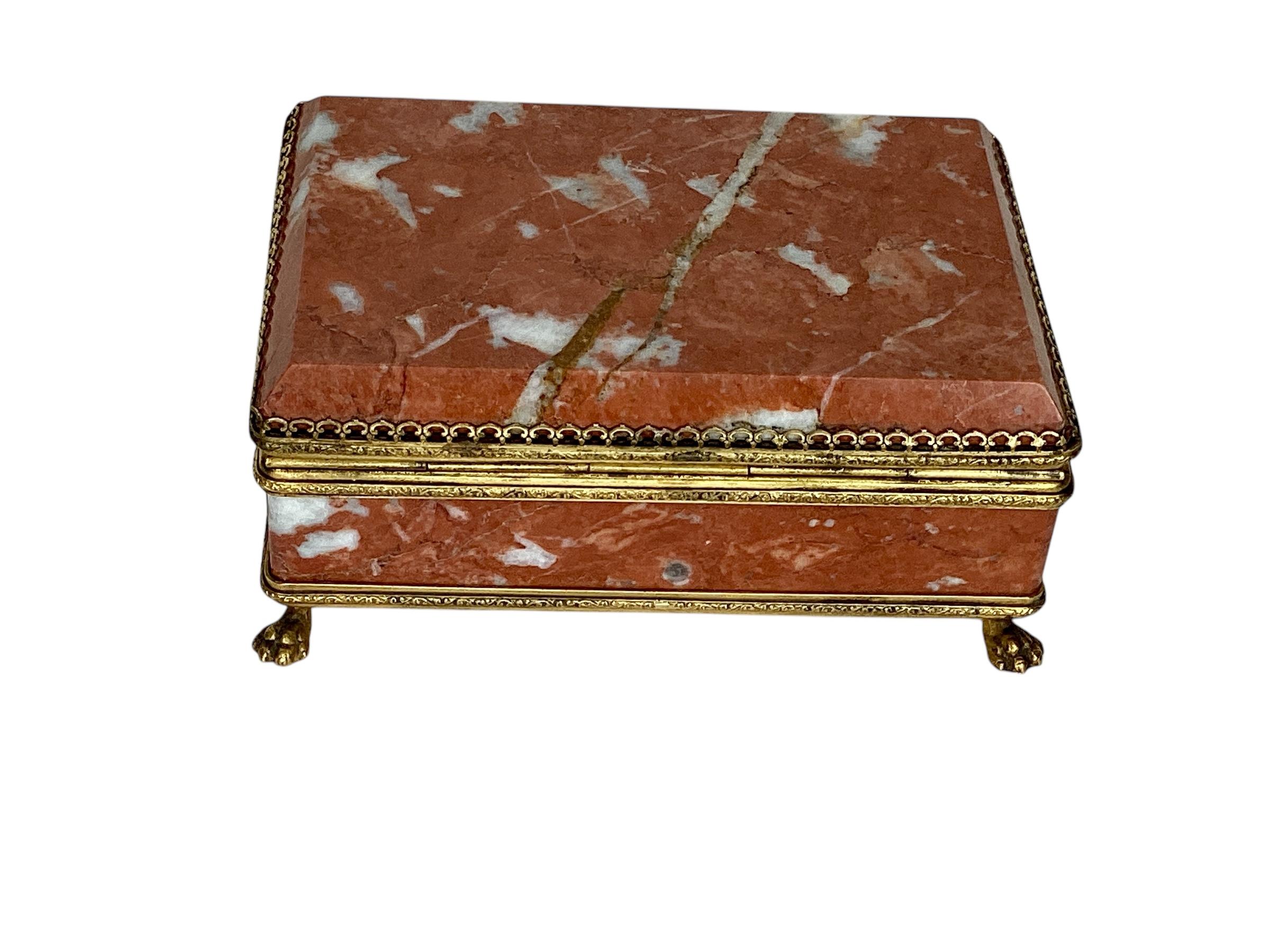 Magnifique boîte en marbre rouge montée en vermeil, datant de la fin du XIXe siècle. L'intérieur est tapissé de bois et la boîte repose sur des pieds en patte d'oie dorés. En très bon état, avec une usure normale des ferrures dorées.