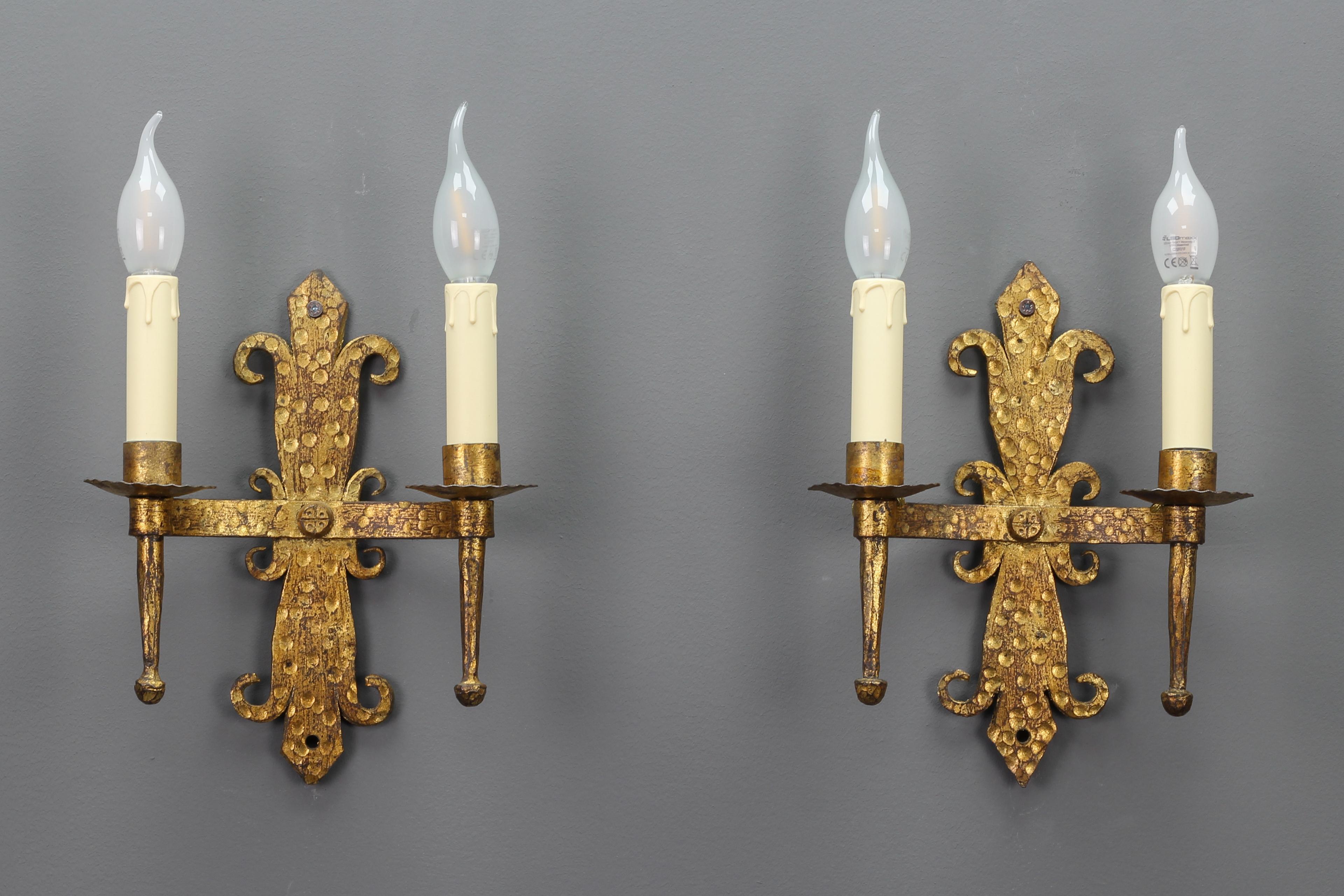 Late 19th-century French gilt wrought iron two-light sconces, set of two.
A beautiful pair of Medieval style sconces, France, from the late 19th century.
These wrought iron wall lamps with a gold-plated patina each have two lights with sockets for