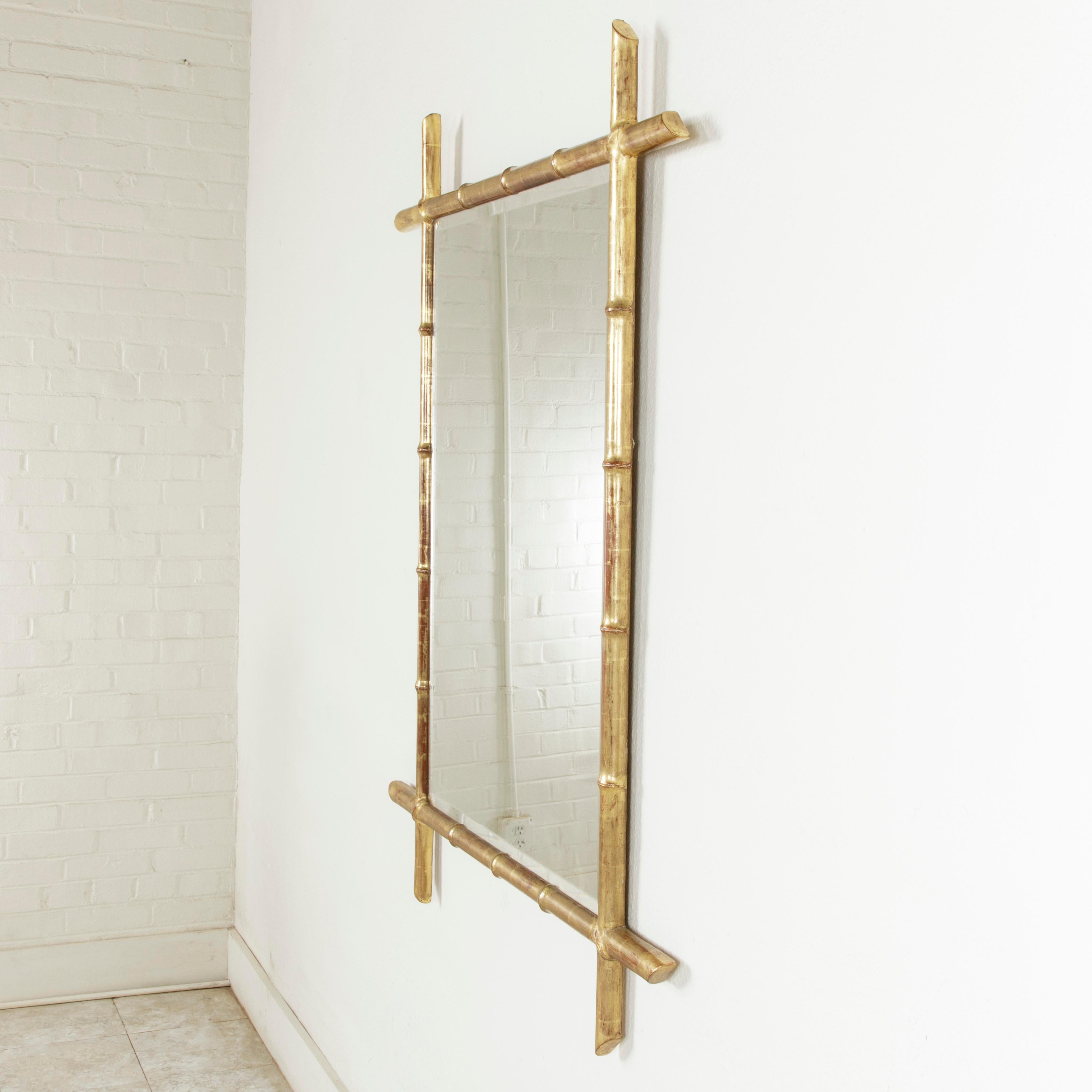 This late 19th century French giltwood mirror features a square faux bamboo frame that surrounds its beveled glass. The bamboo extensions of the frame are cut at the ends at 45 degree angles, giving the mirror a contemporary look. The frame measures