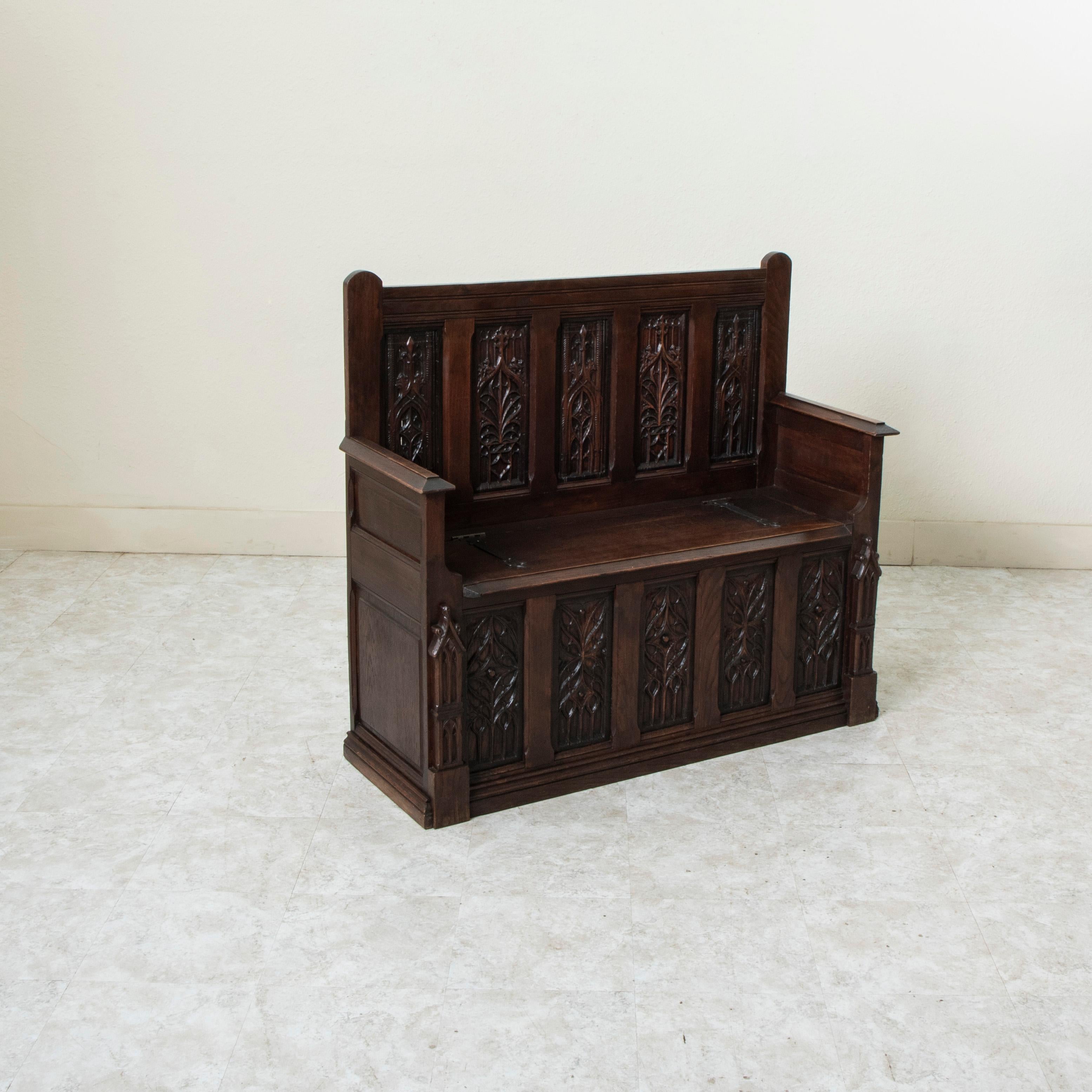 Questa panca in rovere in stile gotico francese della fine del XIX secolo presenta dieci pannelli intagliati a mano nel grembiule inferiore e nello schienale, ciascuno con motivi gotici alternati. Colonne gotiche fiancheggiano i pannelli inferiori