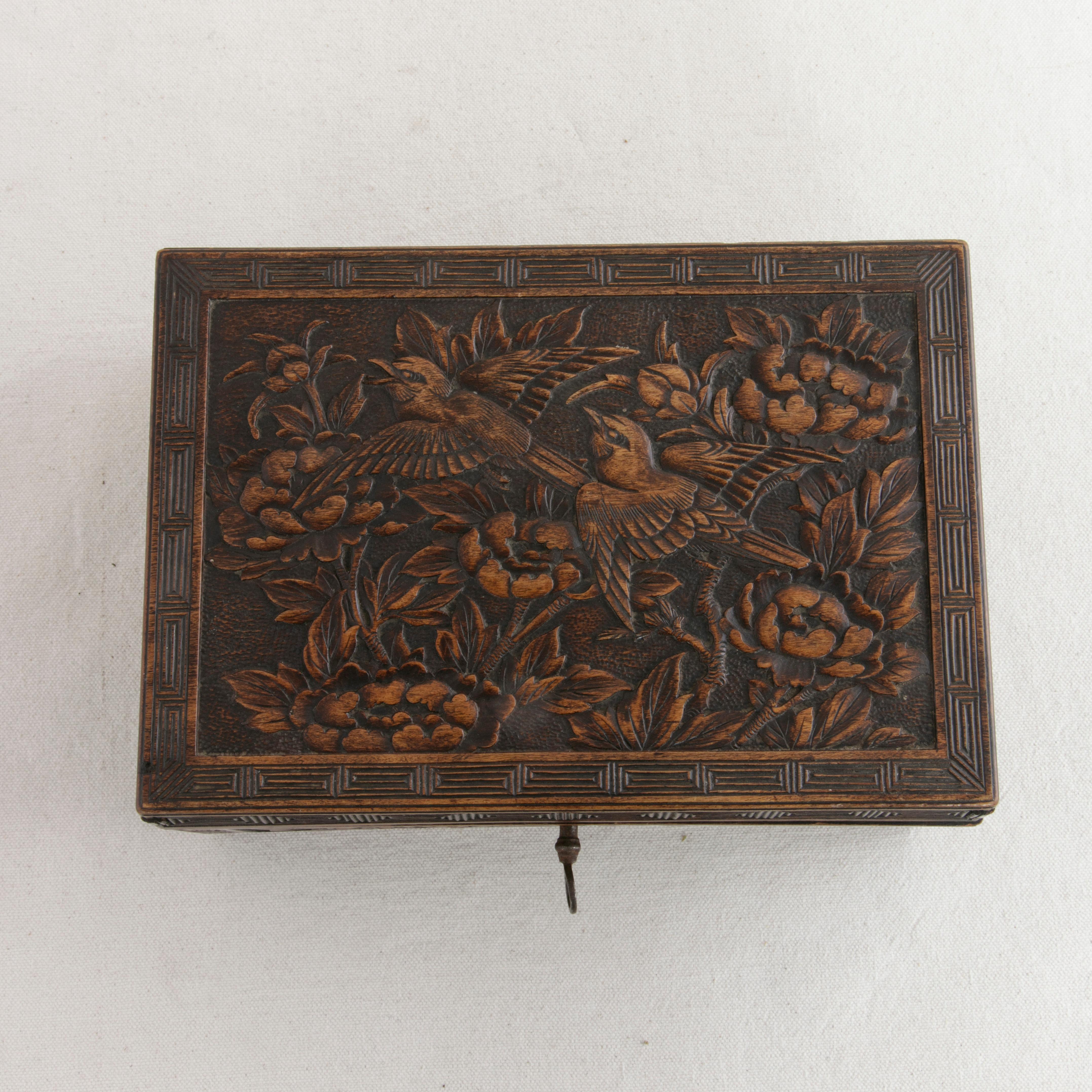 This French hand carved Black Forest box from the late 19th century features very detailed carvings of woodland birds and flowers on the lid with additional carvings of flowers on all sides. A Greek key border surrounds each face. Includes one key,