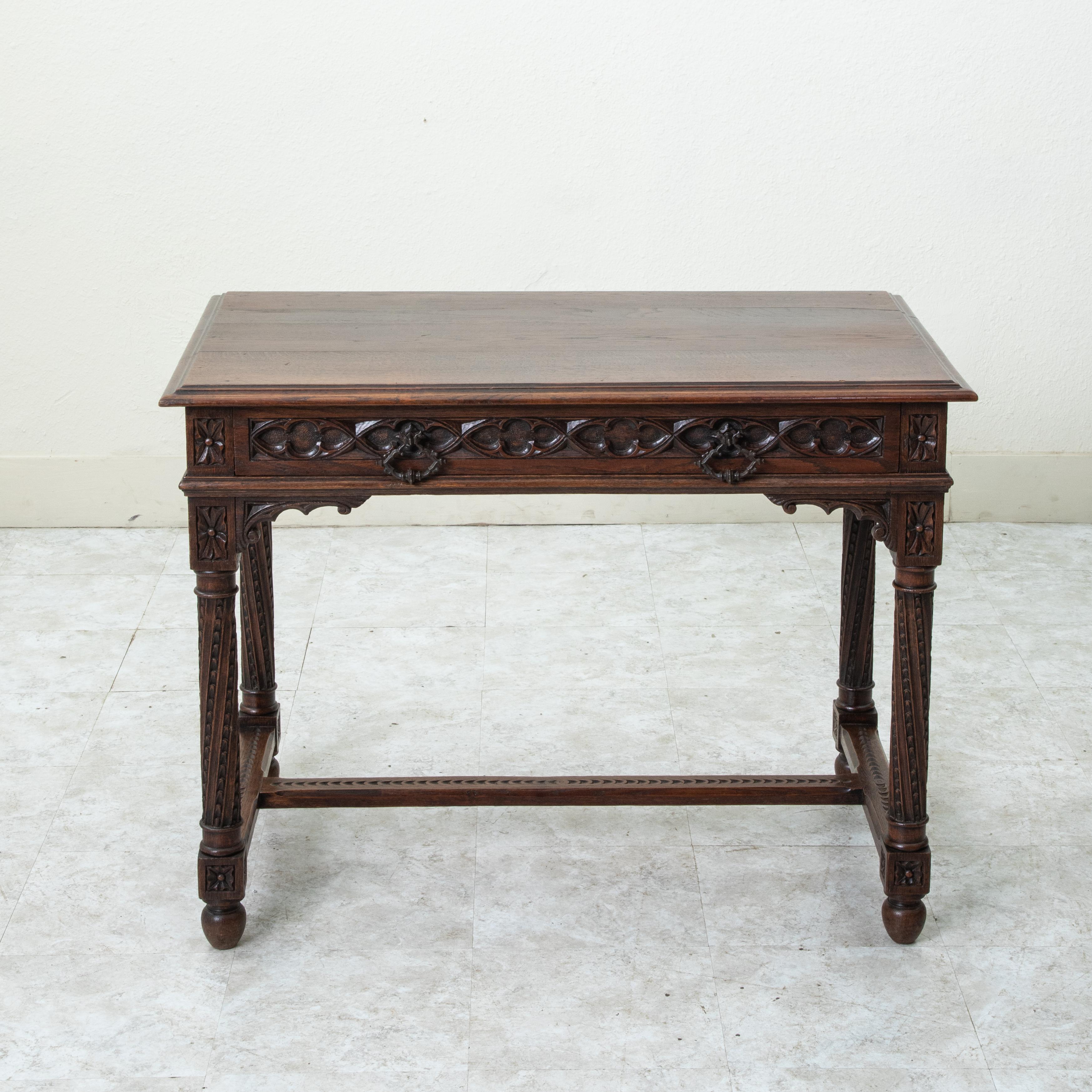 Questa scrivania o tavolo da scrittura in stile gotico francese della fine del XIX secolo è costruita in rovere massiccio e presenta un piano smussato sopra un grembiule con un intreccio gotico intagliato a mano su tutti e quattro i lati. Un