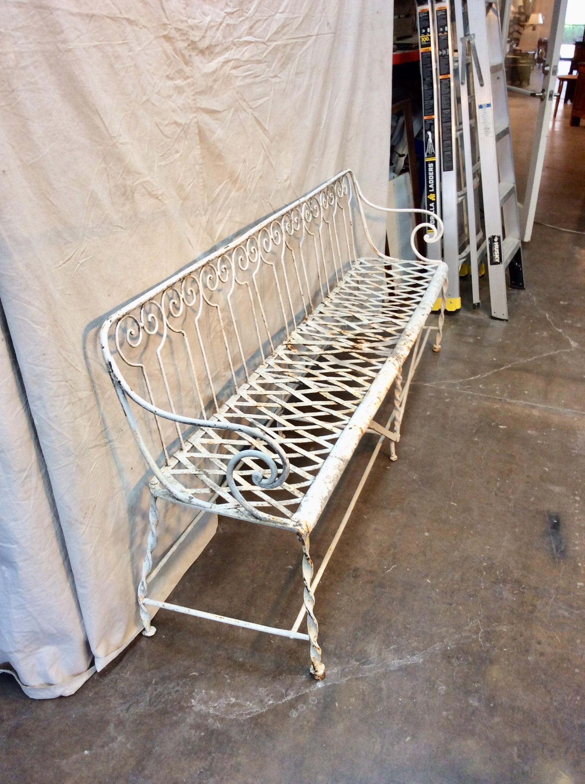 Found in the South of France, this attractive Late 19th century French Hand Forged Iron Garden Bench or Settee features a lattice flat iron seat with a scrolled iron back, arms and legs. The piece is supported with iron stretchers and crossbars.