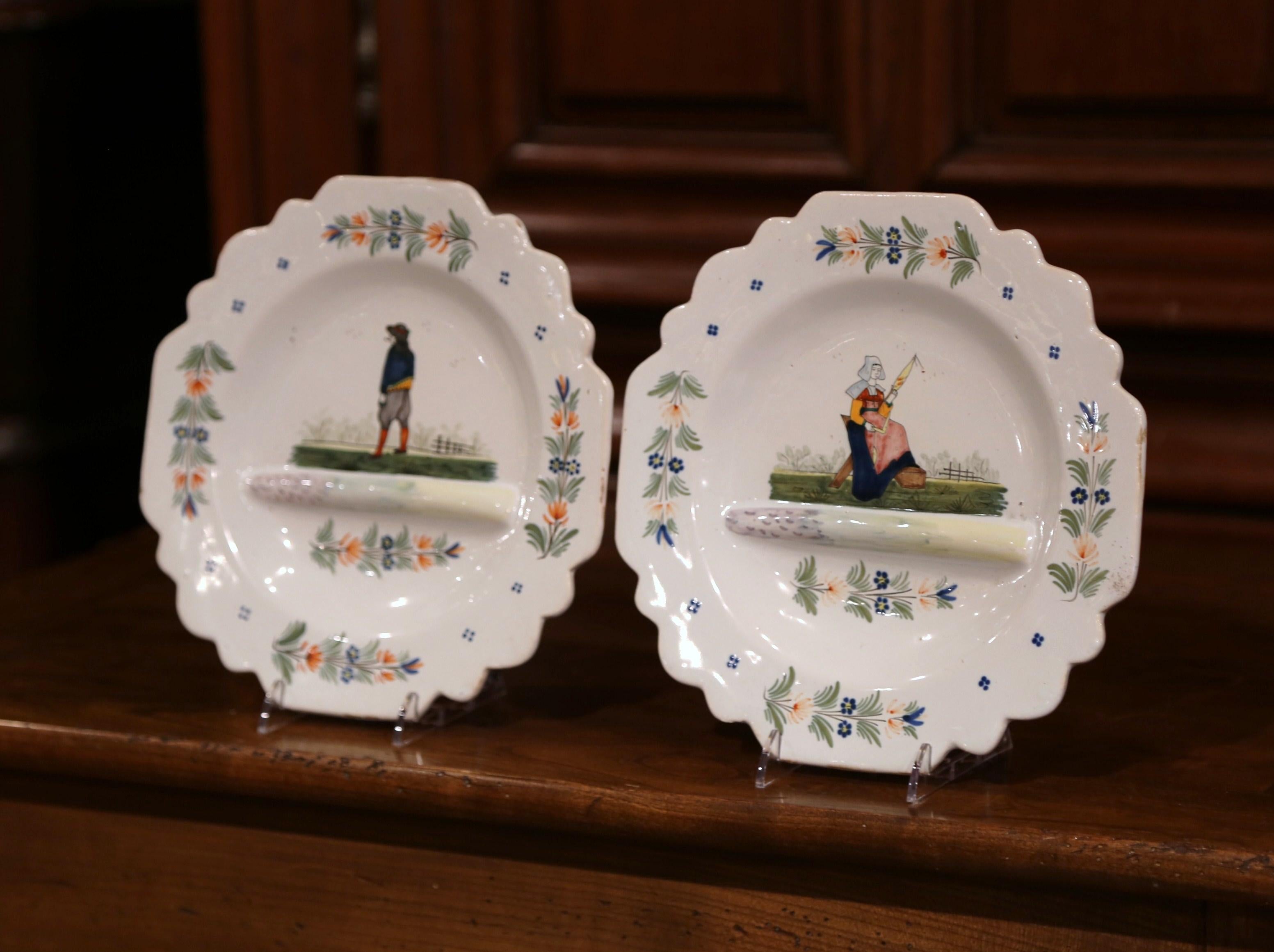 Decorate a shelf with this pair of antique decorative plates from Brittany, France. Crafted circa 1883-1895, each faience plate is hand painted with traditional Breton figure motifs along with floral embellishments. Both plates are in excellent