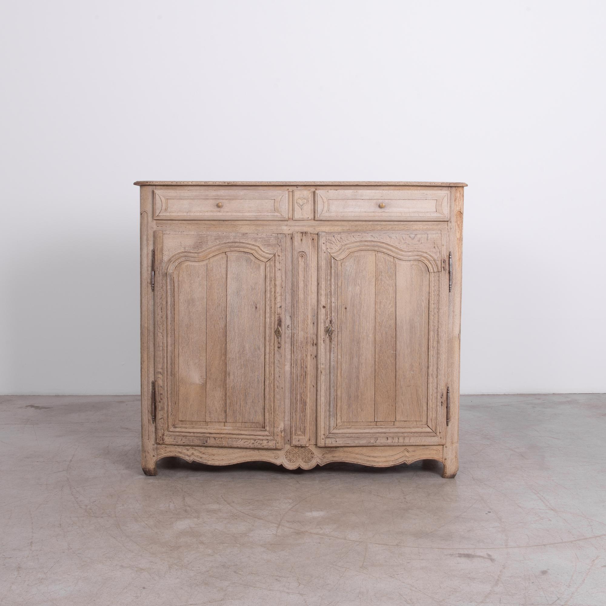 A two-drawer and door style cabinet from France, circa 1880. Durable frame and panel construction is a timeless technique, adorned with period decoration carved in old-growth European oak. Great rustic finish gives this piece charming character,