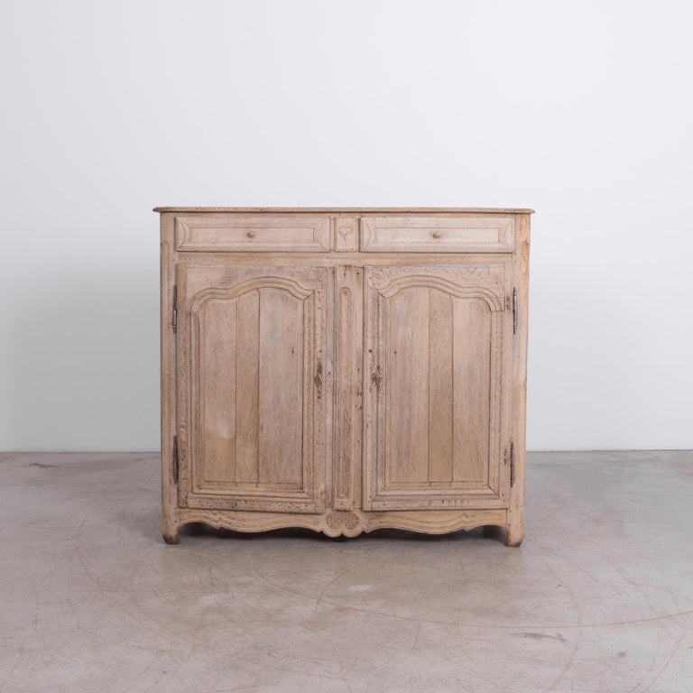 A two-drawer and door style cabinet from France, circa 1880. Durable frame and panel construction is a timeless technique, adorned with period decoration carved in old-growth European oak. Great rustic finish gives this piece charming character,