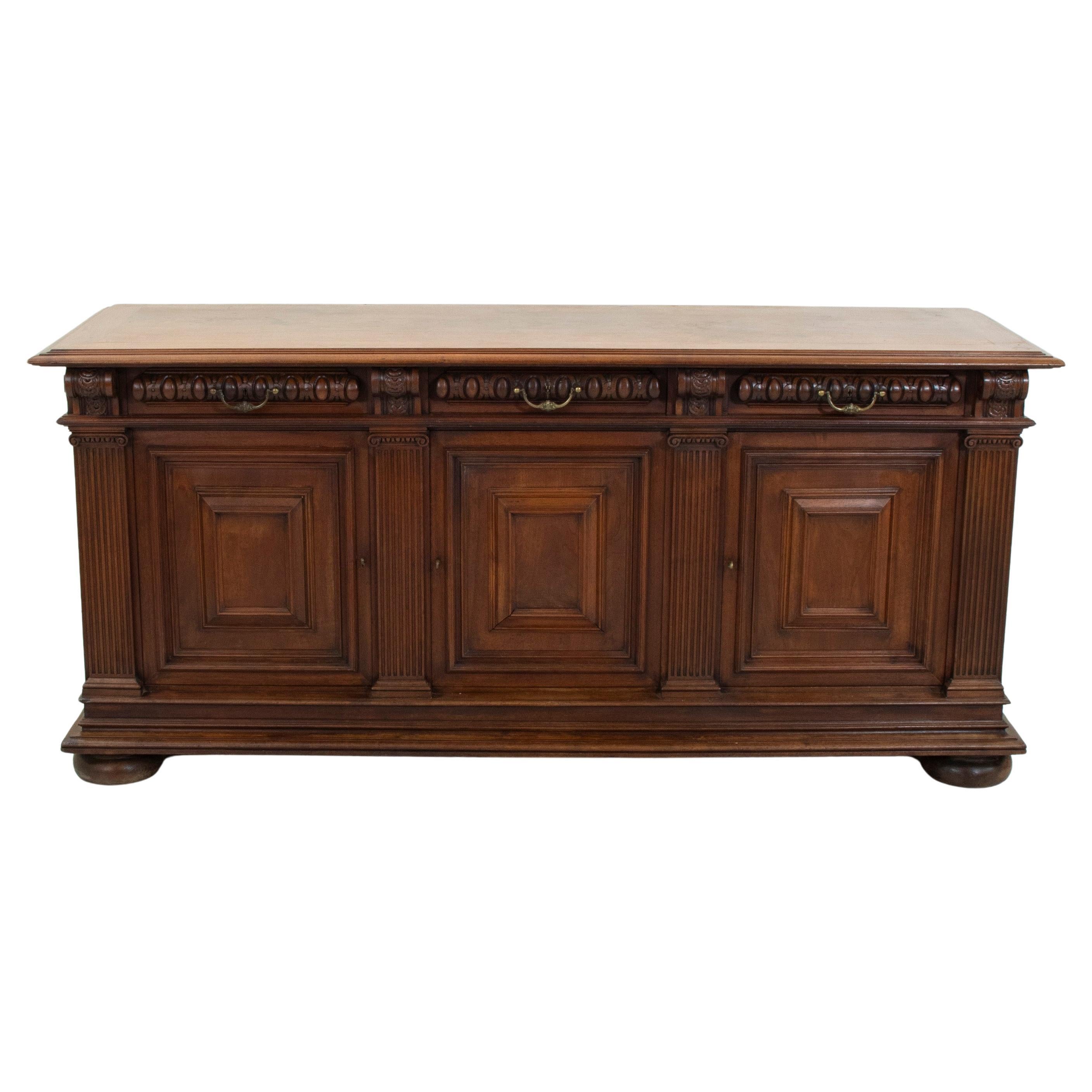 Questa credenza in noce in stile HENRY II della fine del XIX secolo presenta quattro semicolonne scanalate con capitelli a volute e un piano in noce smussato. Tre cassetti a coda di rondine che si inseriscono nel grembiule sono decorati con un