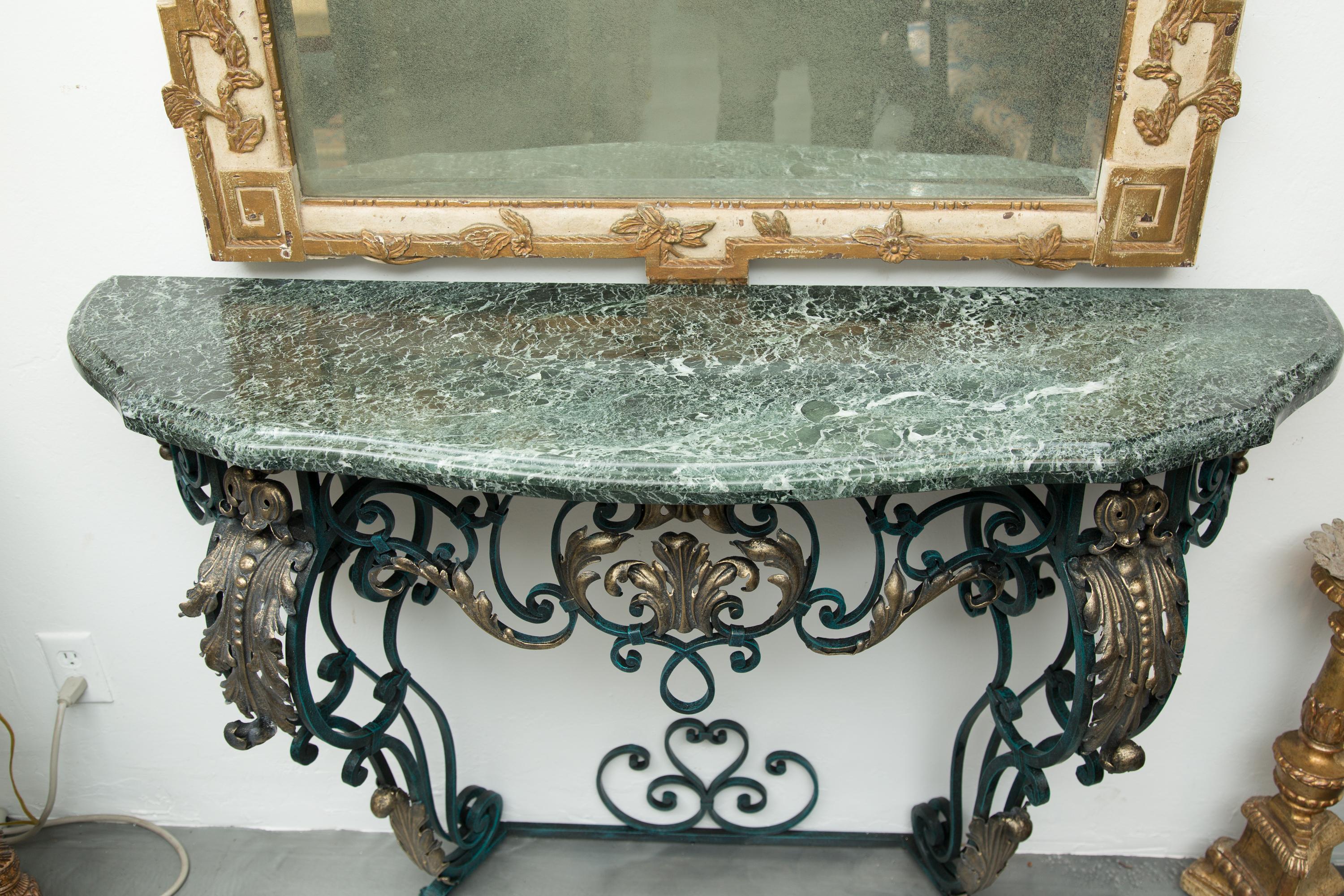 This is an attractive 19th century restored verdigris and parcel-gilt French console. The variegated green marble top is situated on an ornate scrolling iron frieze, supported by graceful cabriole-form legs joined by a bottom stretcher.