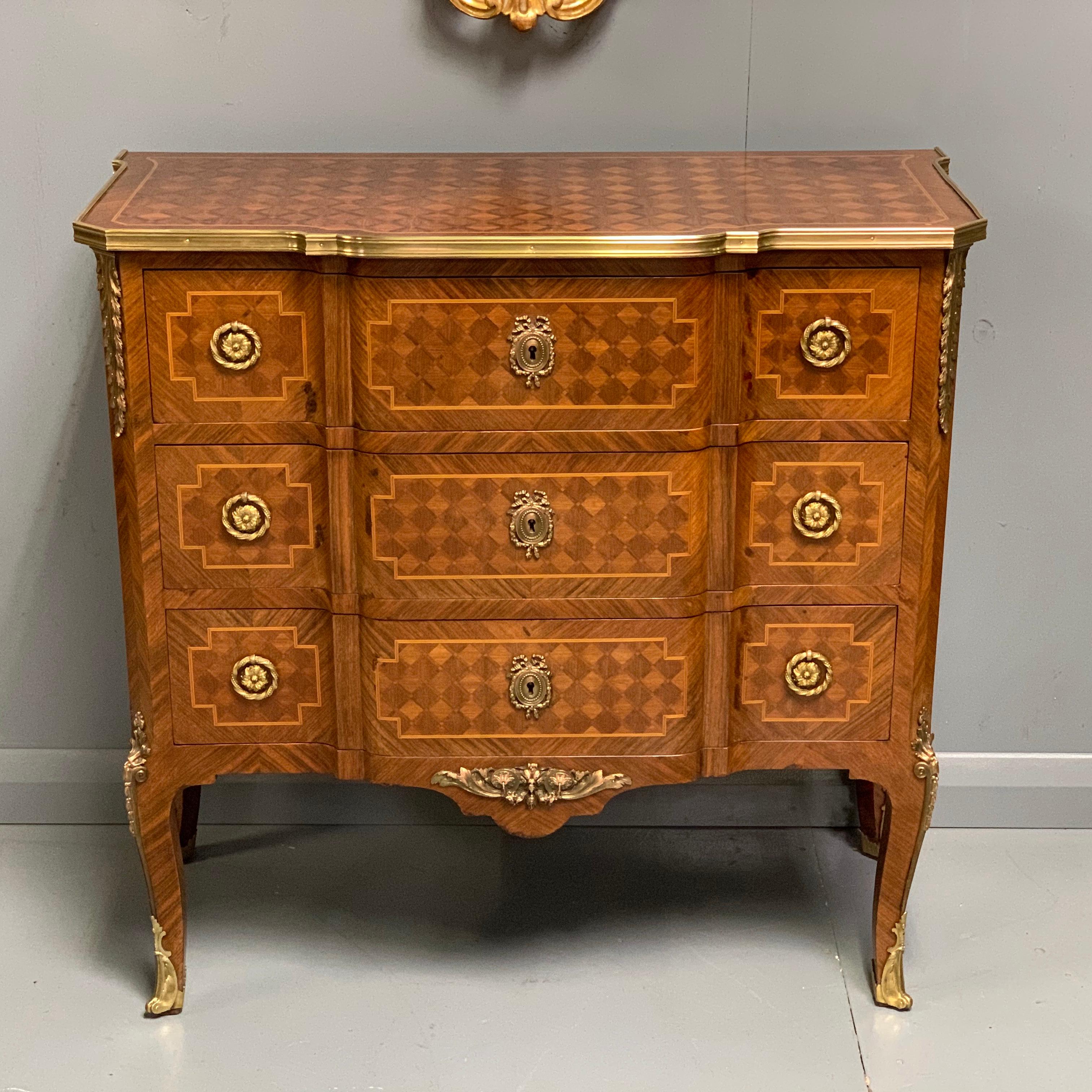 A very good quality and decorative French kingwood and geometric parquetry small commode of three drawers with fantastic original brass mounts and sabot mounts to the feet.

This is a very elegant chest with the slight proportions but also how it