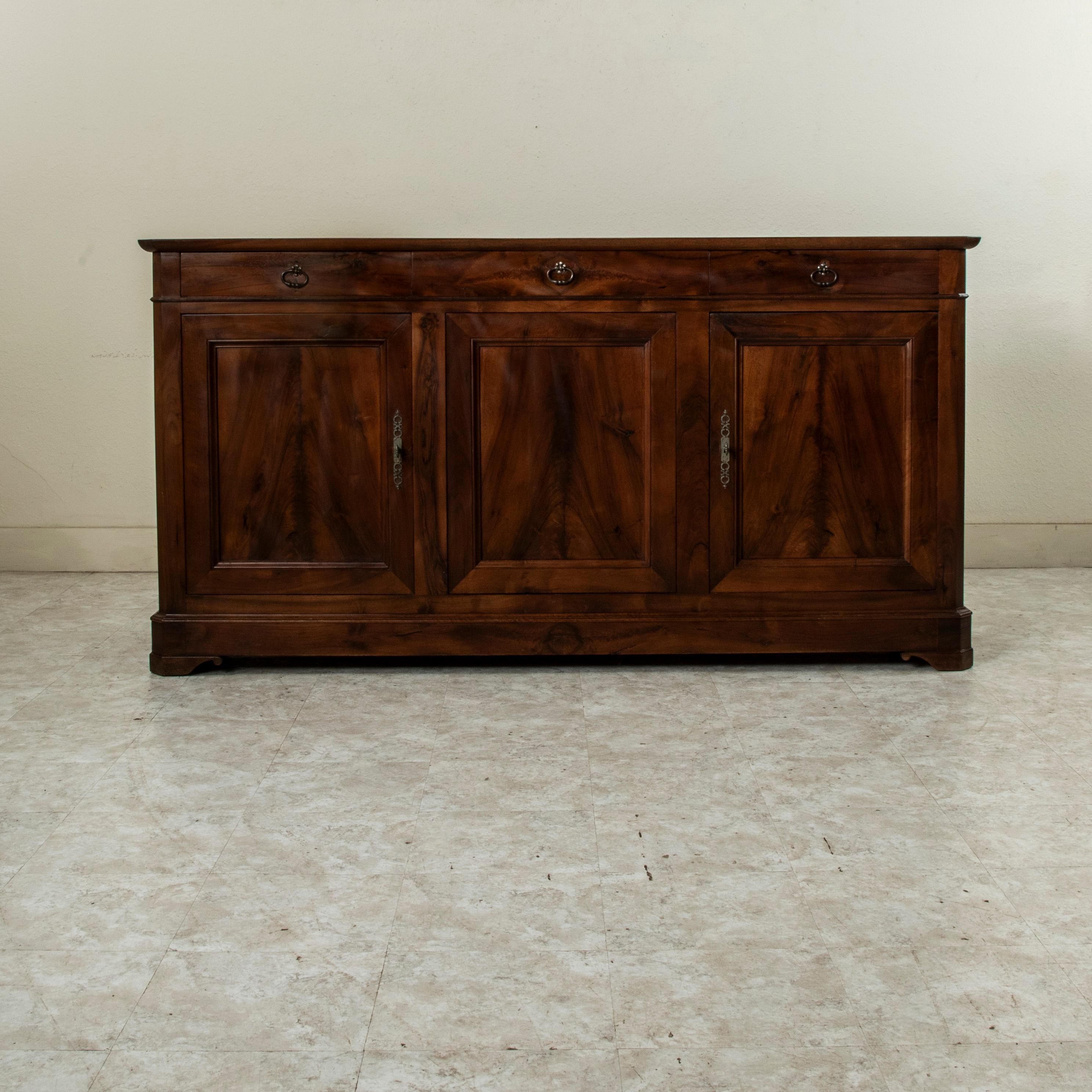 This late nineteenth century French Louis Philippe style enfilade or sideboard is constructed of solid walnut with hand pegged joinery. This server features three book matched walnut doors that open to reveal an interior with a long single shelf.