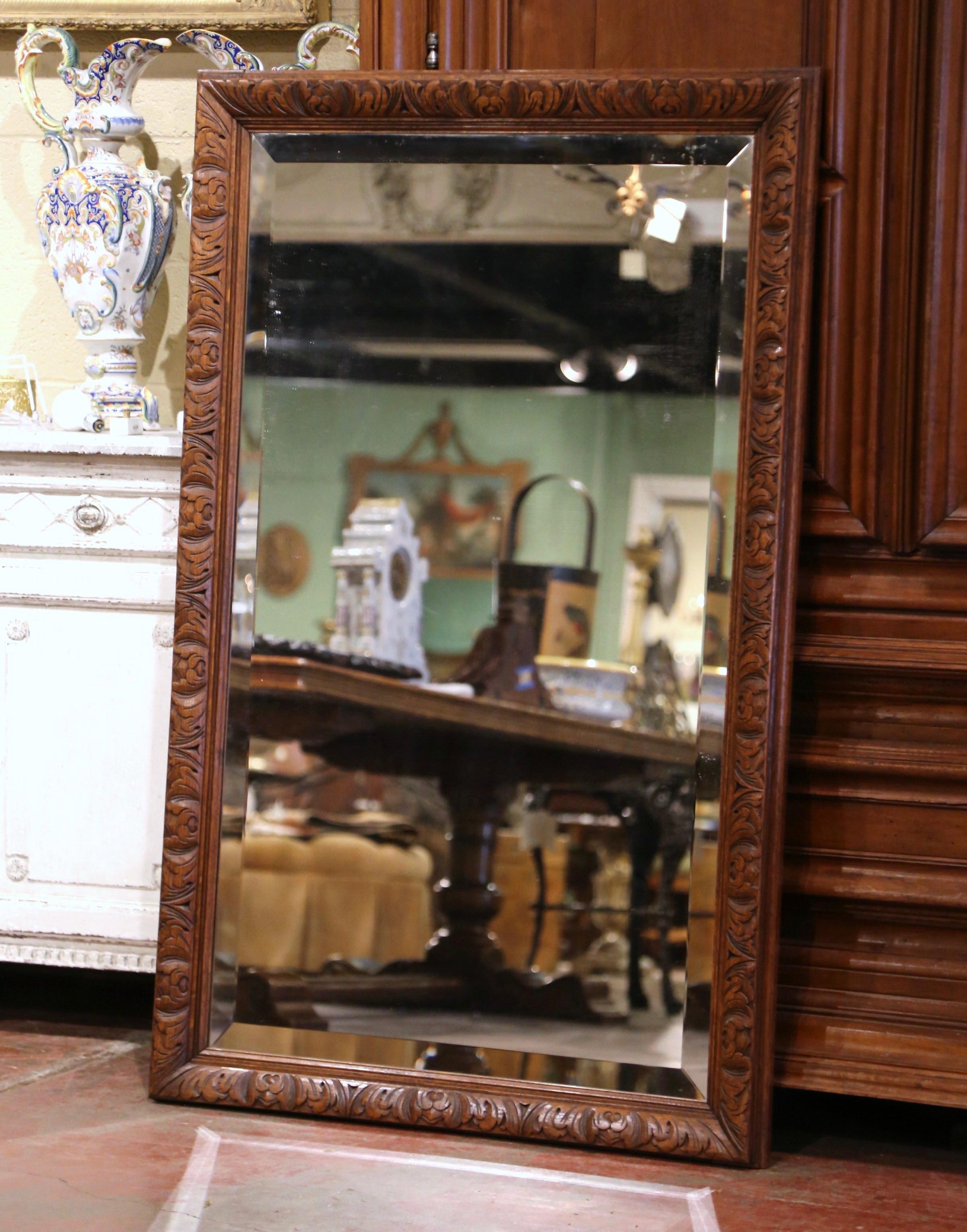 Crafted in France circa 1880, and built of oak wood, the antique mirror is rectangular in shape, and could be used vertically or horizontally. Decorated with hand carved acanthus leaf motifs throughout, the wall mirror is dressed with a beveled