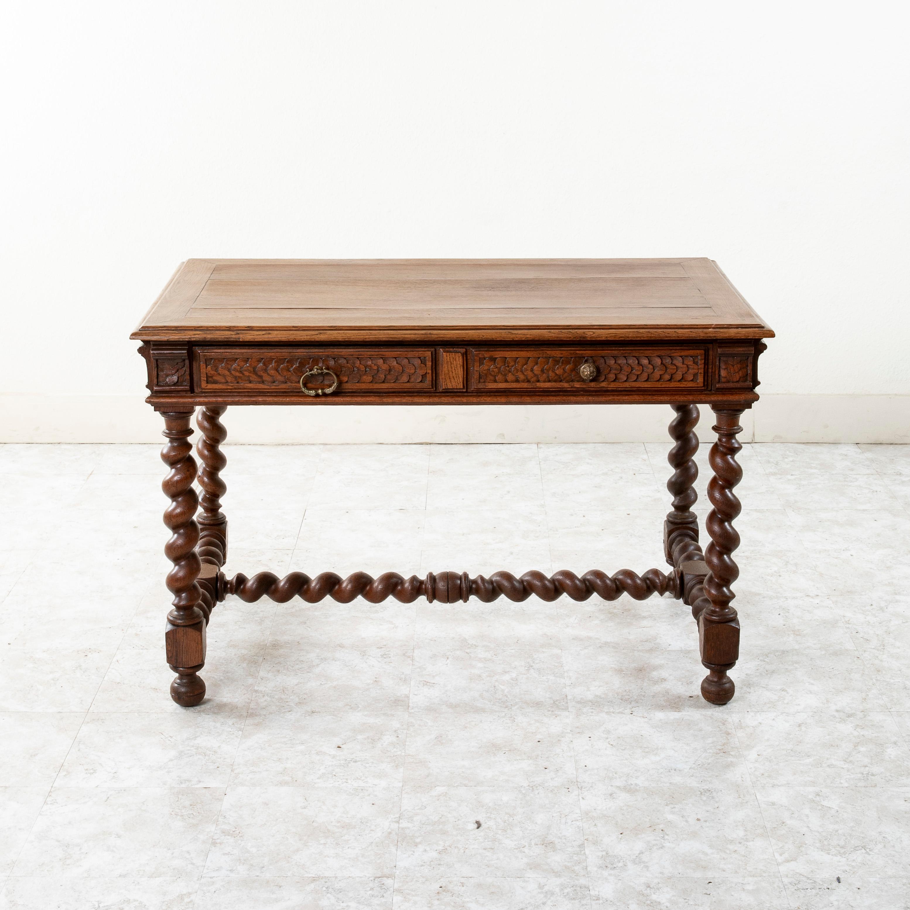 This French Louis XIII style walnut desk from the late 19th century features a beveled top and hand-carved capitals at the corners. A hand carved overlapping quatrefoil motif details each side of the piece. A long single drawer concealed in the