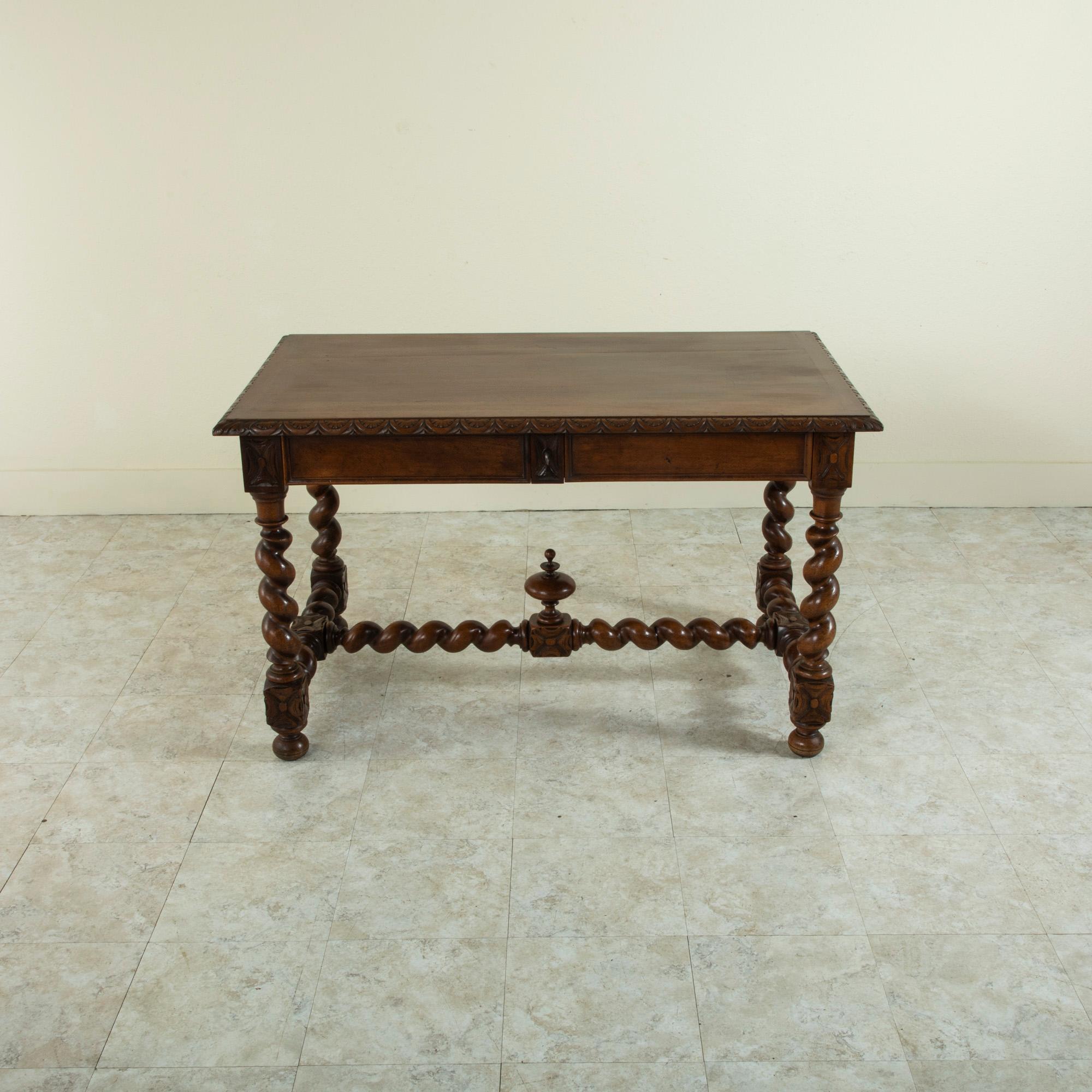 This French Louis XIII style walnut desk from the late 19th century features a hand carved egg and dart pattern around its beveled top and hand-carved rosettes at the corners. Two drawers are concealed in the apron on one side, one with an interior
