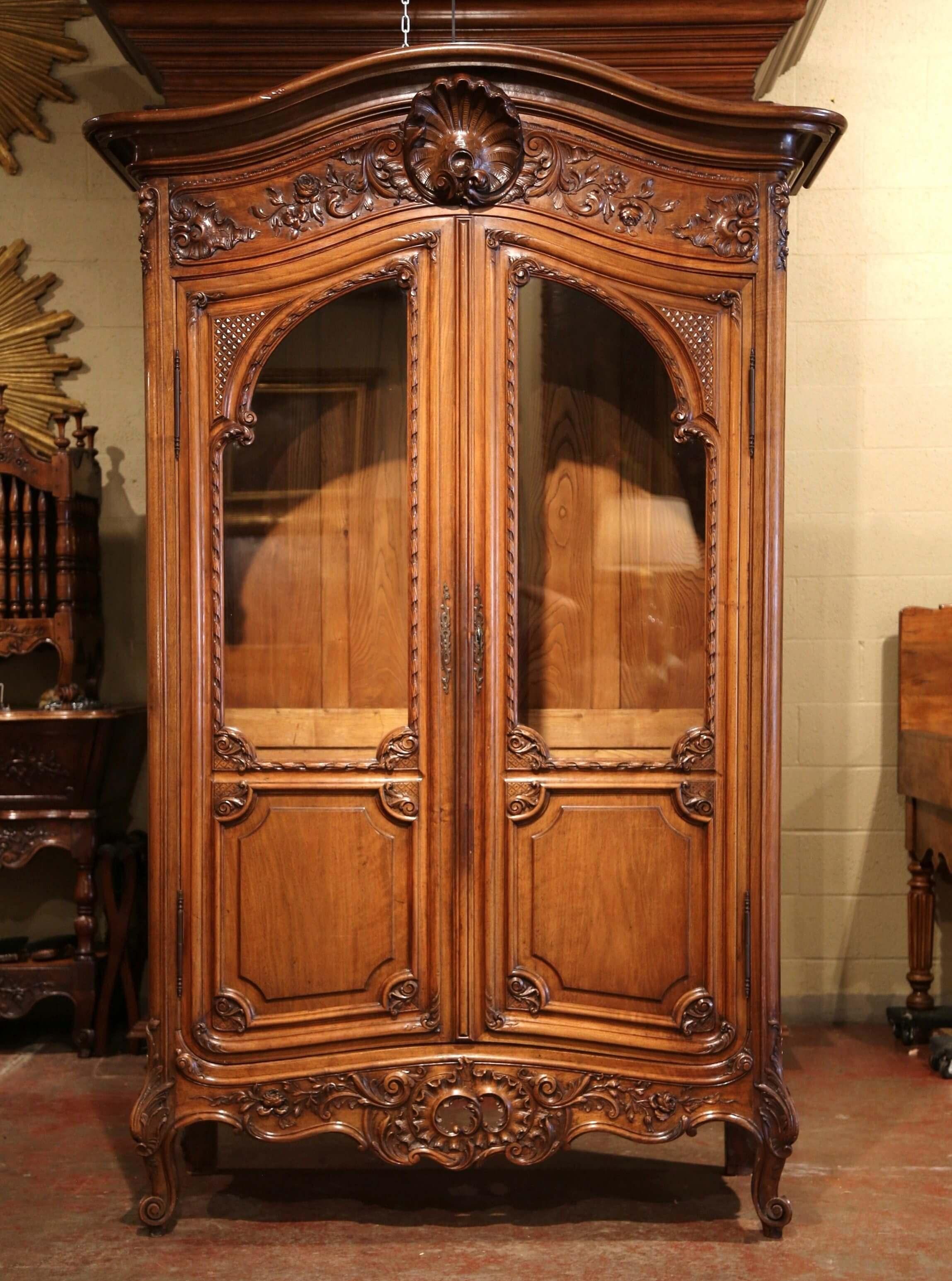 This antique cabinet was crafted in southern France, circa 1890. The armoire sits on scrolled feet decorated with hand carved acanthus leaves over a very ornate apron embellished with a pierced center shell, and floral and leaf decor. The bonnet top